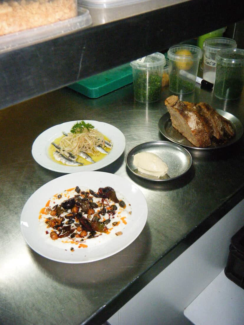 Teller mit verschiedenen Speisen, darunter Fisch, Brot und Joghurt.