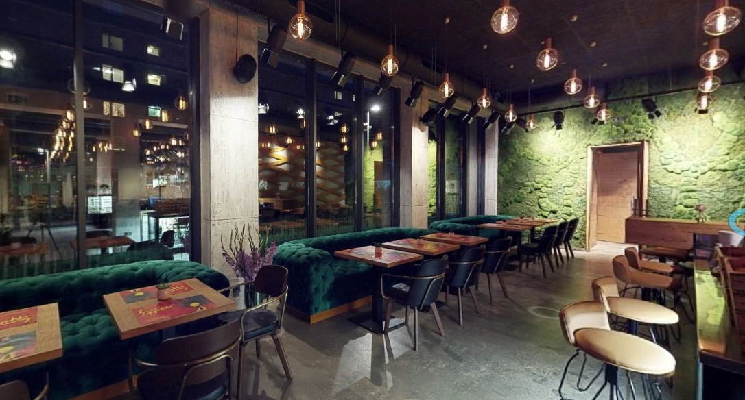 Restaurant mit grünen Samtsofas und Mooswand