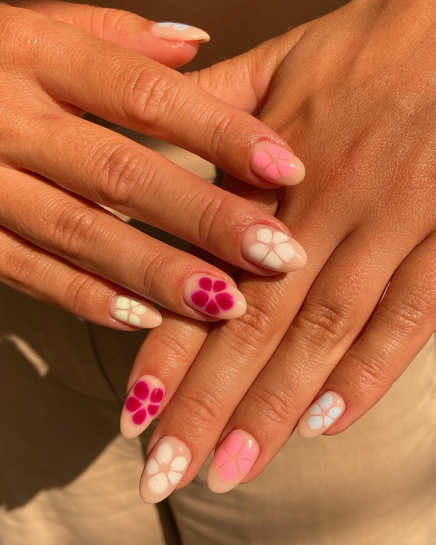 Nägel mit tropischen Blumen in weiß, rosa und pink auf natürlichem Untergrund