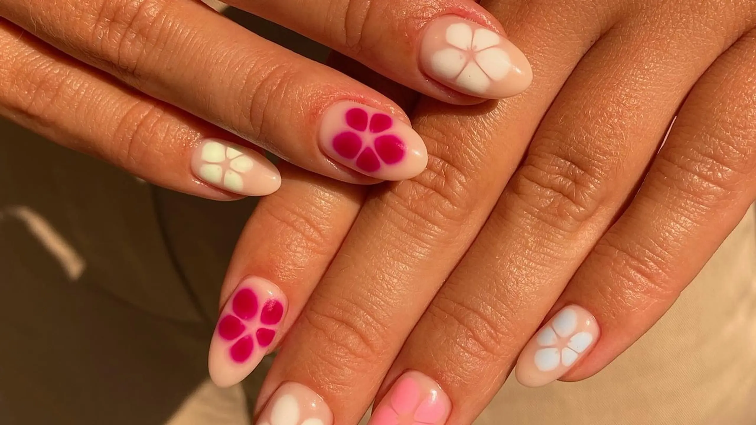 Nägel mit tropischen Blumen in weiß, rosa und pink auf natürlichem Untergrund