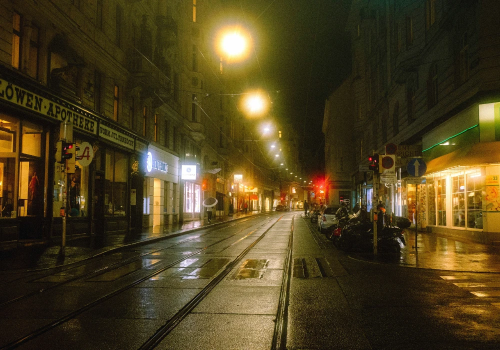 Nasse Straße mit Straßenbahngleisen in der Nacht