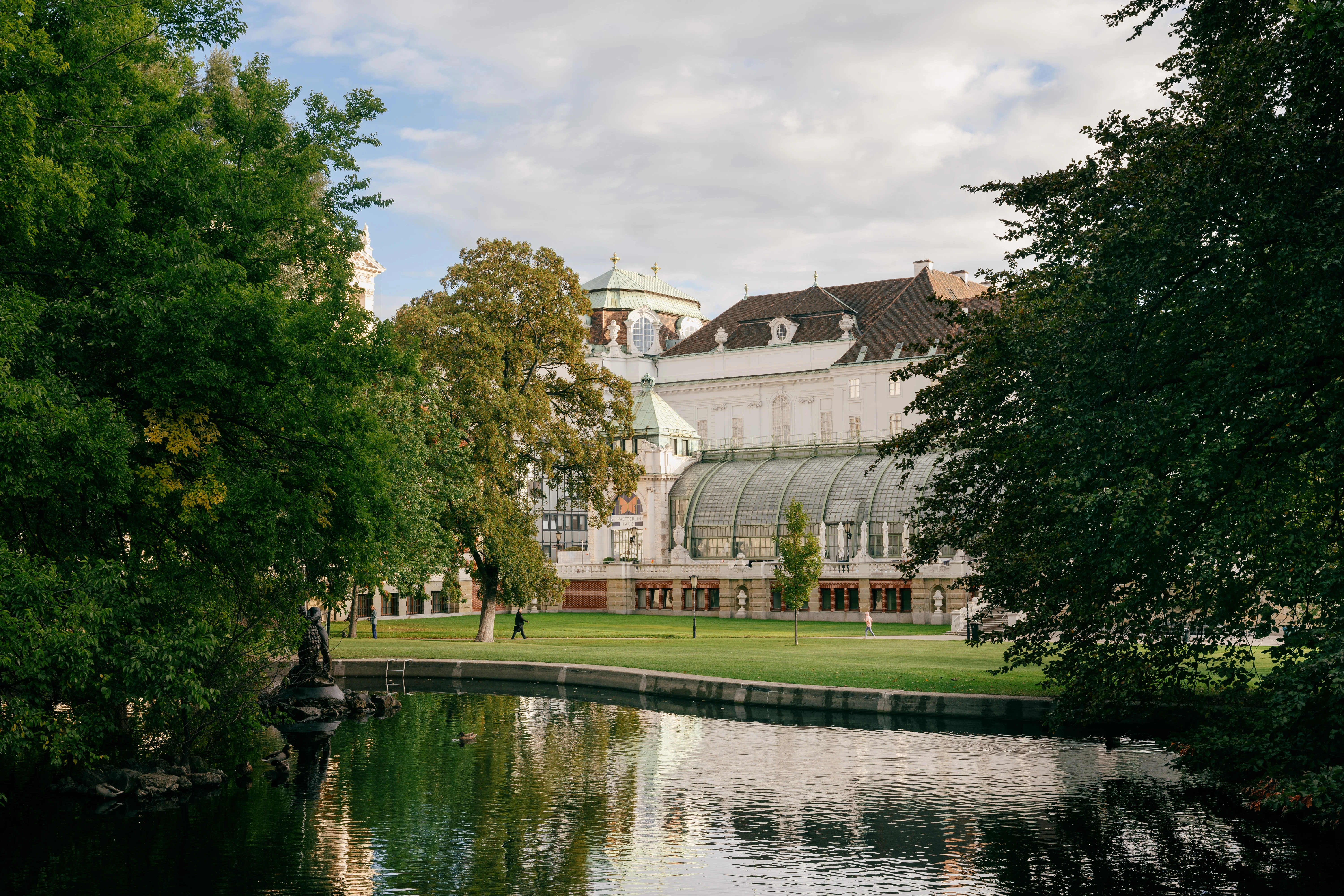Blick auf den Burggarten mit historischen Gebäuden und einem ruhigen Teich.