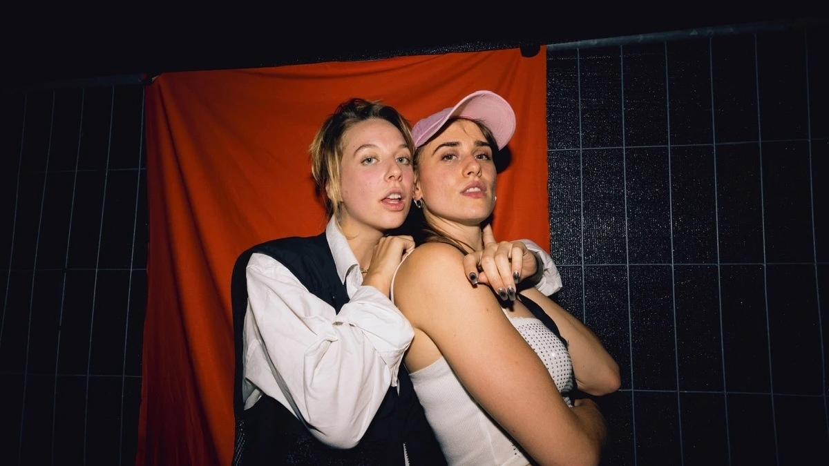 Zwei junge Frauen posieren vor rotem Hintergrund