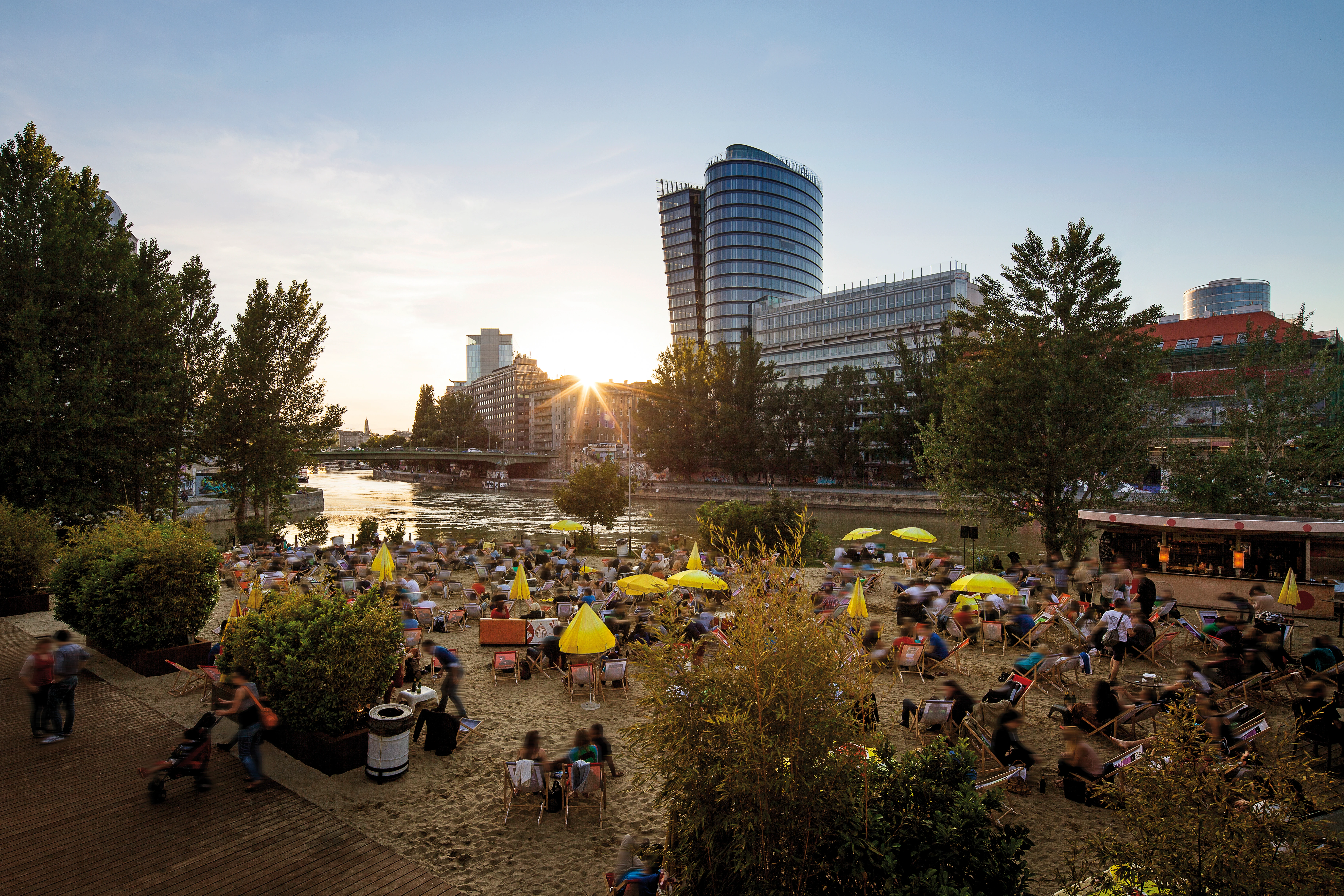 Strandbar Herrmann am Donaukanal. Eine beliebte Bar in Wien am Donaukanal mit Sandstrand, Liegestühlen und entspannter Atmosphäre. Perfekt für Sommerabende.