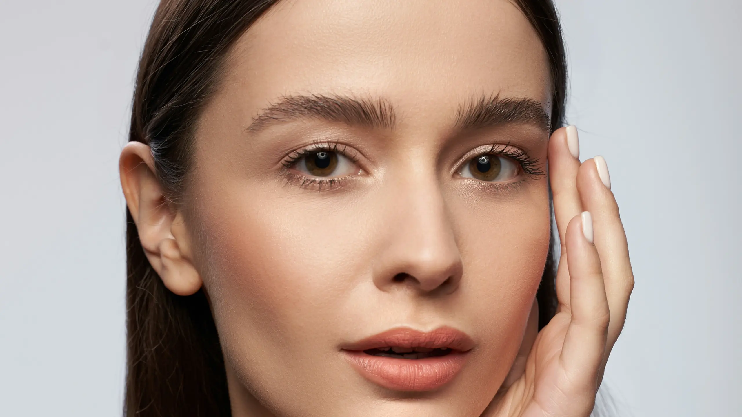 Frau vor grauem Huntergrund und natürlich geschminktem Teint