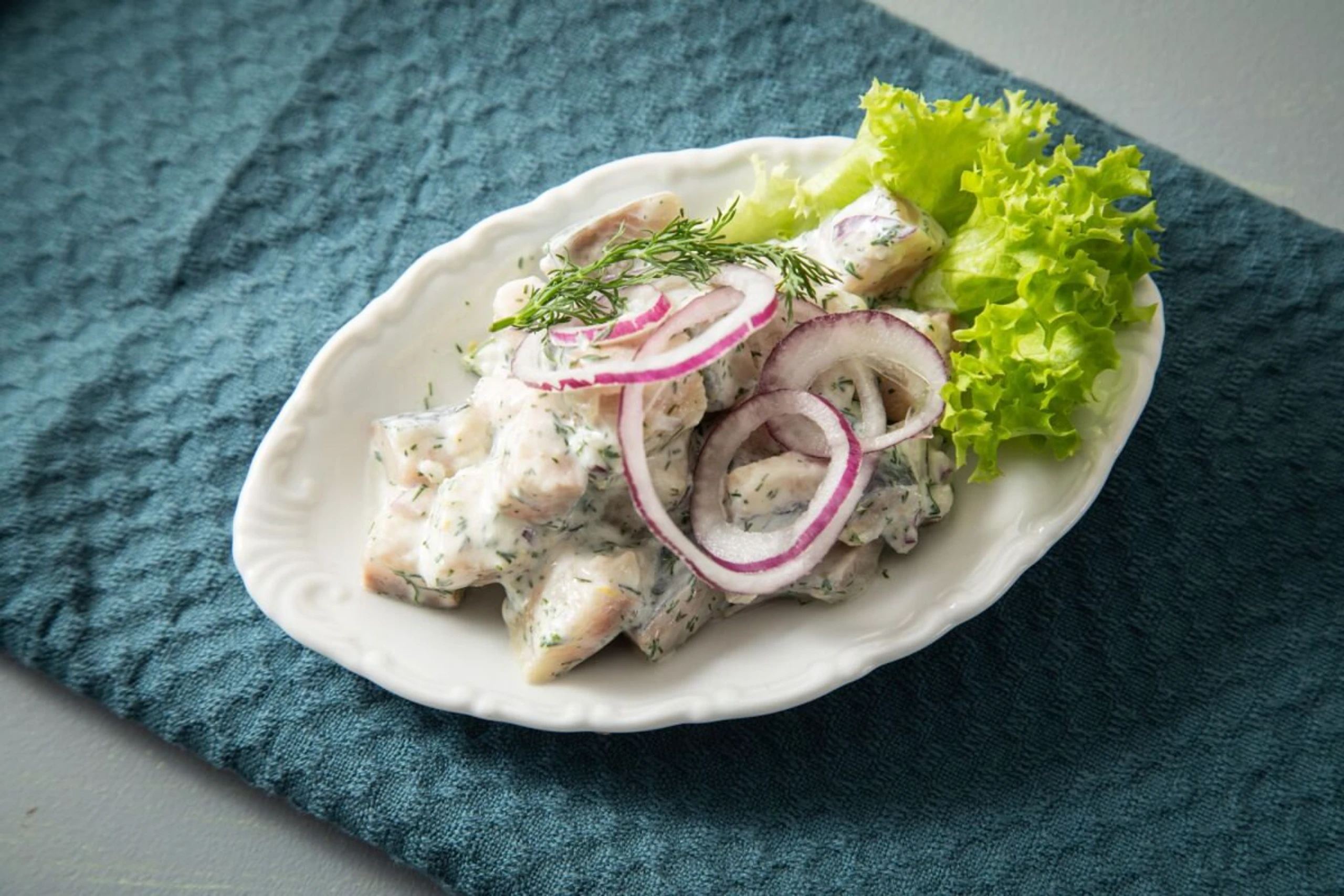 Der klassische Heringsalat wird mit Zwiebeln und Obers angerichtet