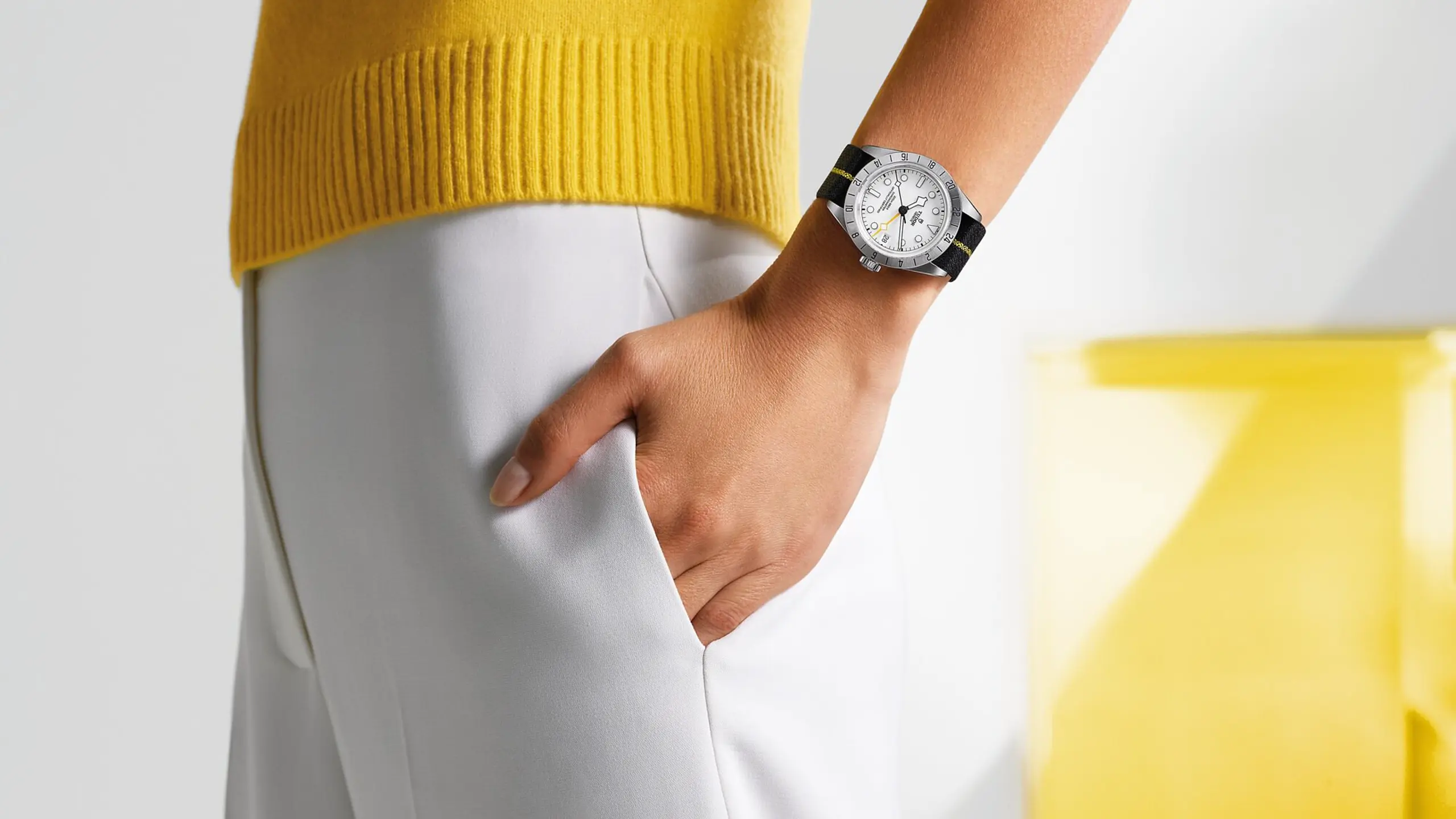 © FOTOS: BEIGESTELLT (3), JOELLE NEUENSCHWANDER, DIODE SA - DENIS HAYOUN, SHUTTERSTOCK man sieht den Arm einer Person, die eine Uhr trägt. Sie trägt eine weiße Hose und einen gelben Pullover.
