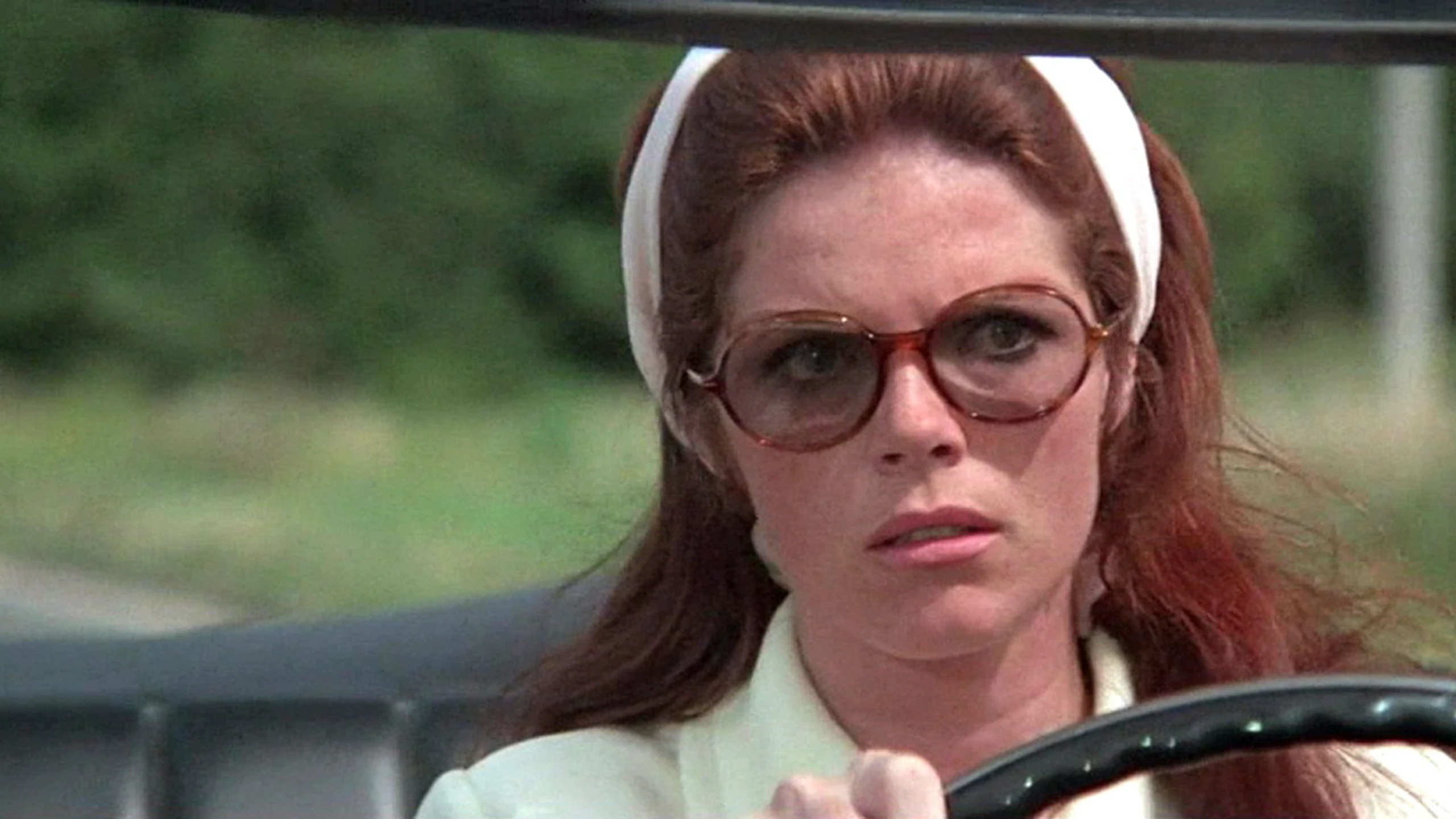 Die Dame im Auto mit Brille und Gewehr
