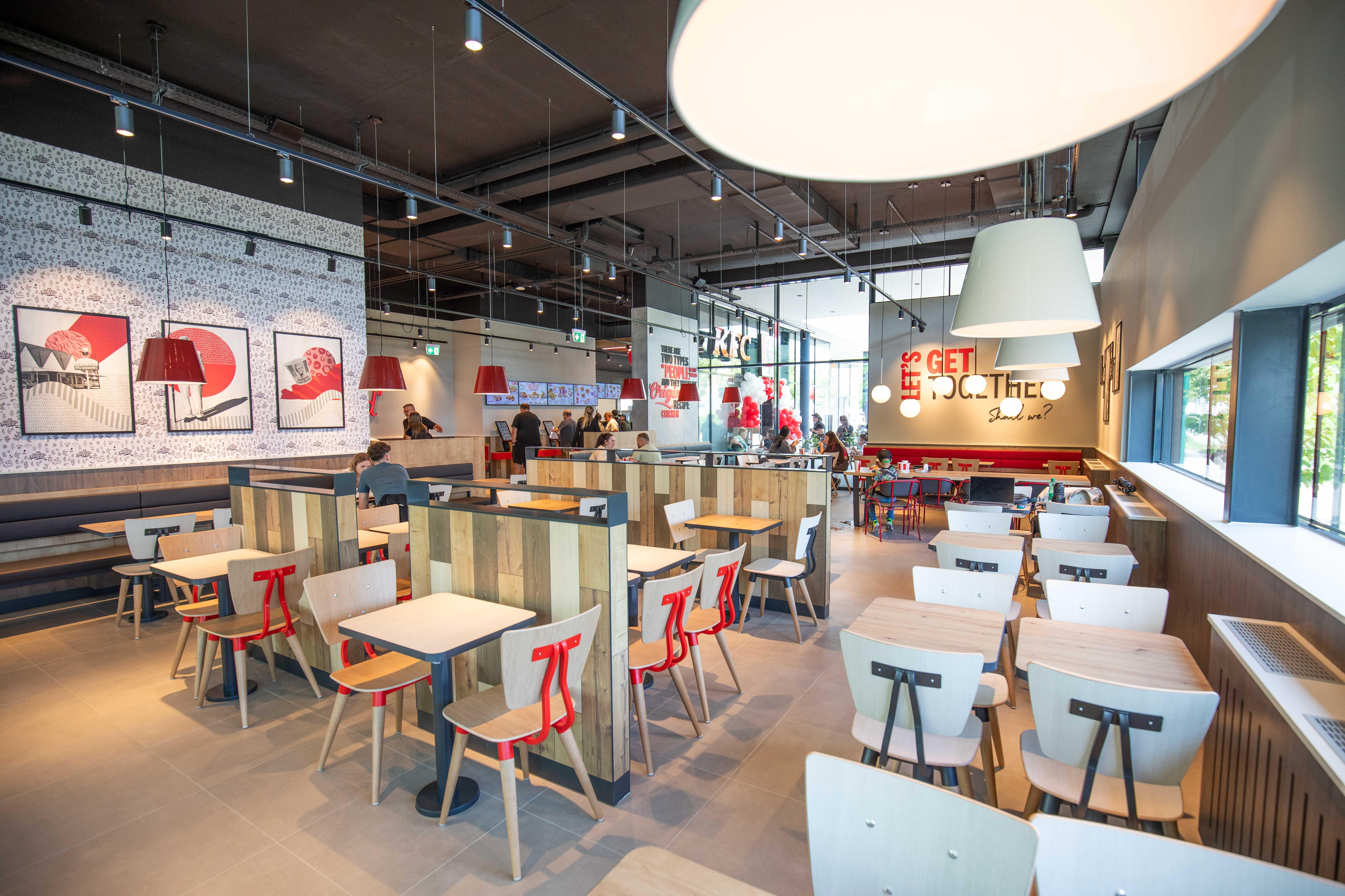 Sitzbereich der KFC-Filiale Wels mit Wandschriftzug „Let's get together“