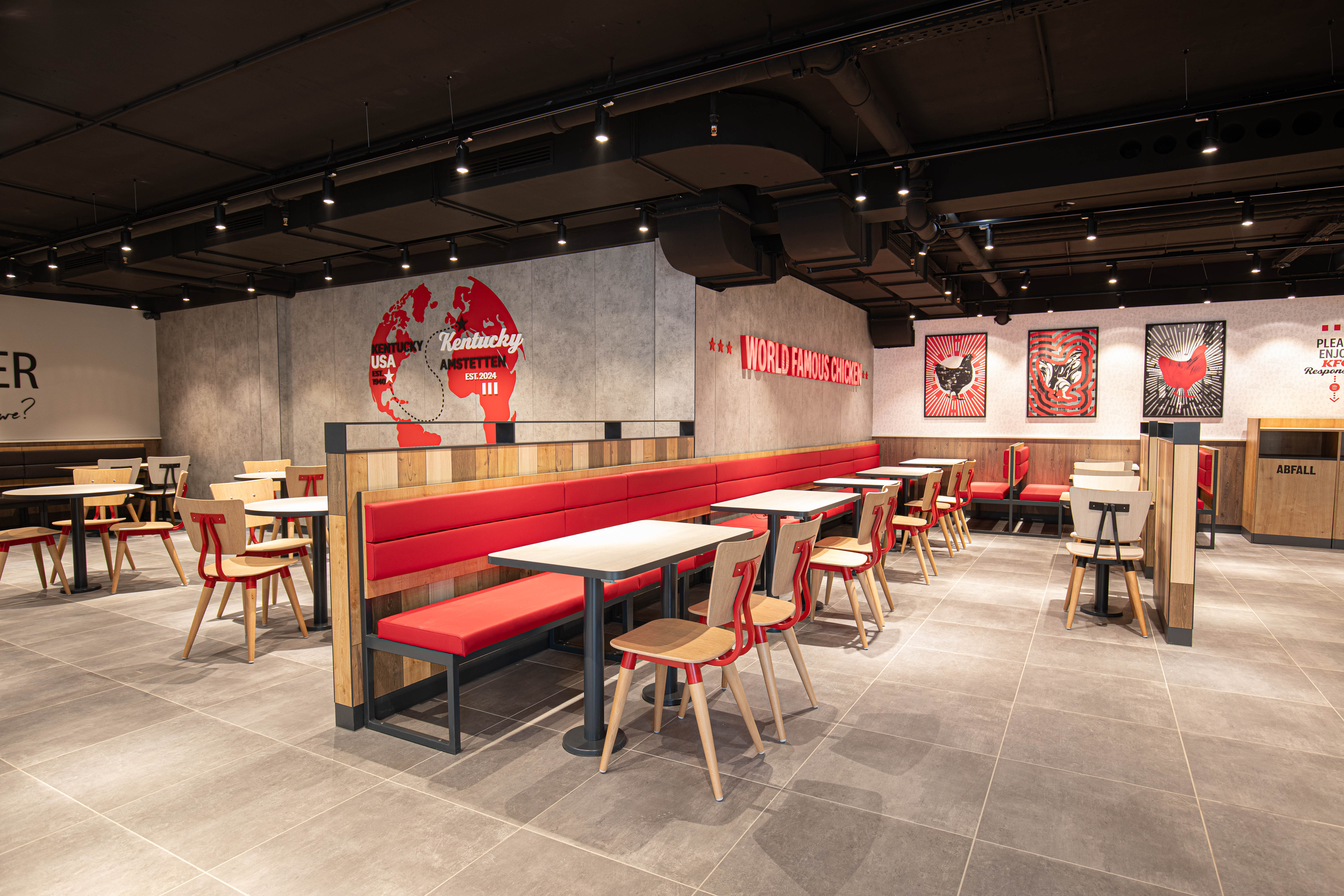 Innenraum der KFC-Filiale Amstetten mit roten Sitzbänken und Weltkarten-Wandbild