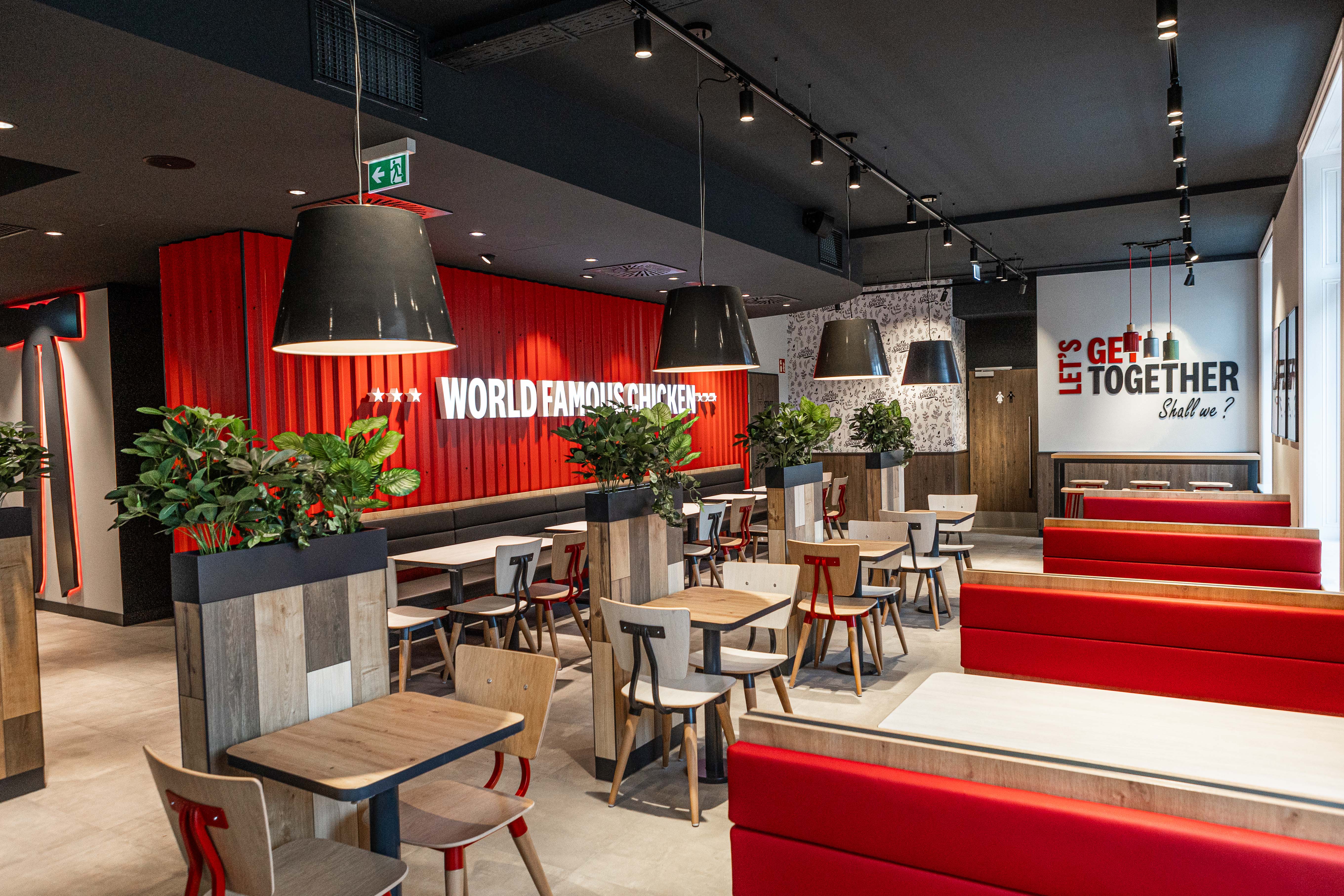 Gastraum der KFC-Filiale St. Pölten mit roten Sitzbänken und Wandschriftzug 'World Famous Chicken'