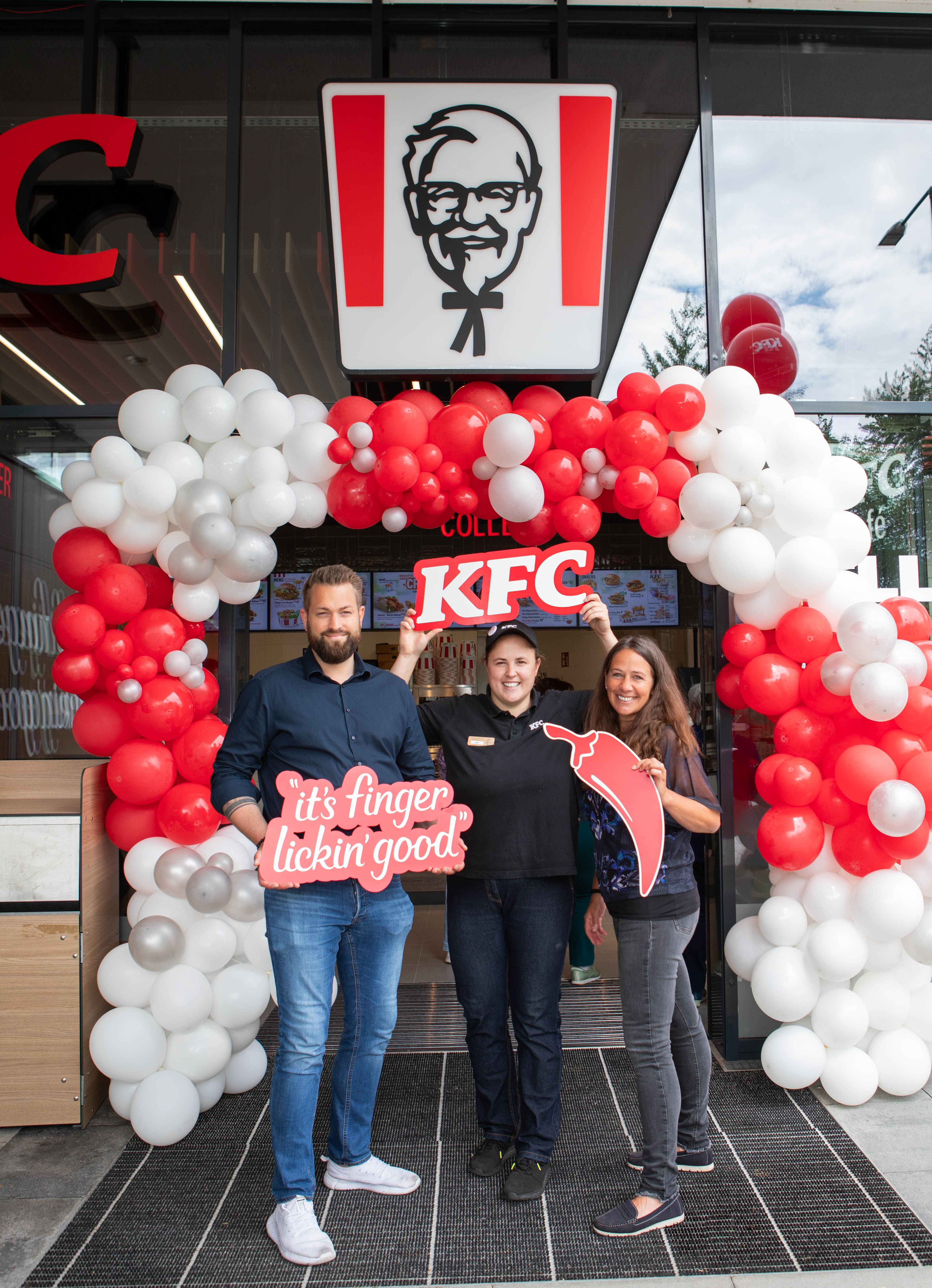 Eröffnung der KFC-Filiale Wels: drei Personen vor Ballonbogen am Eingang