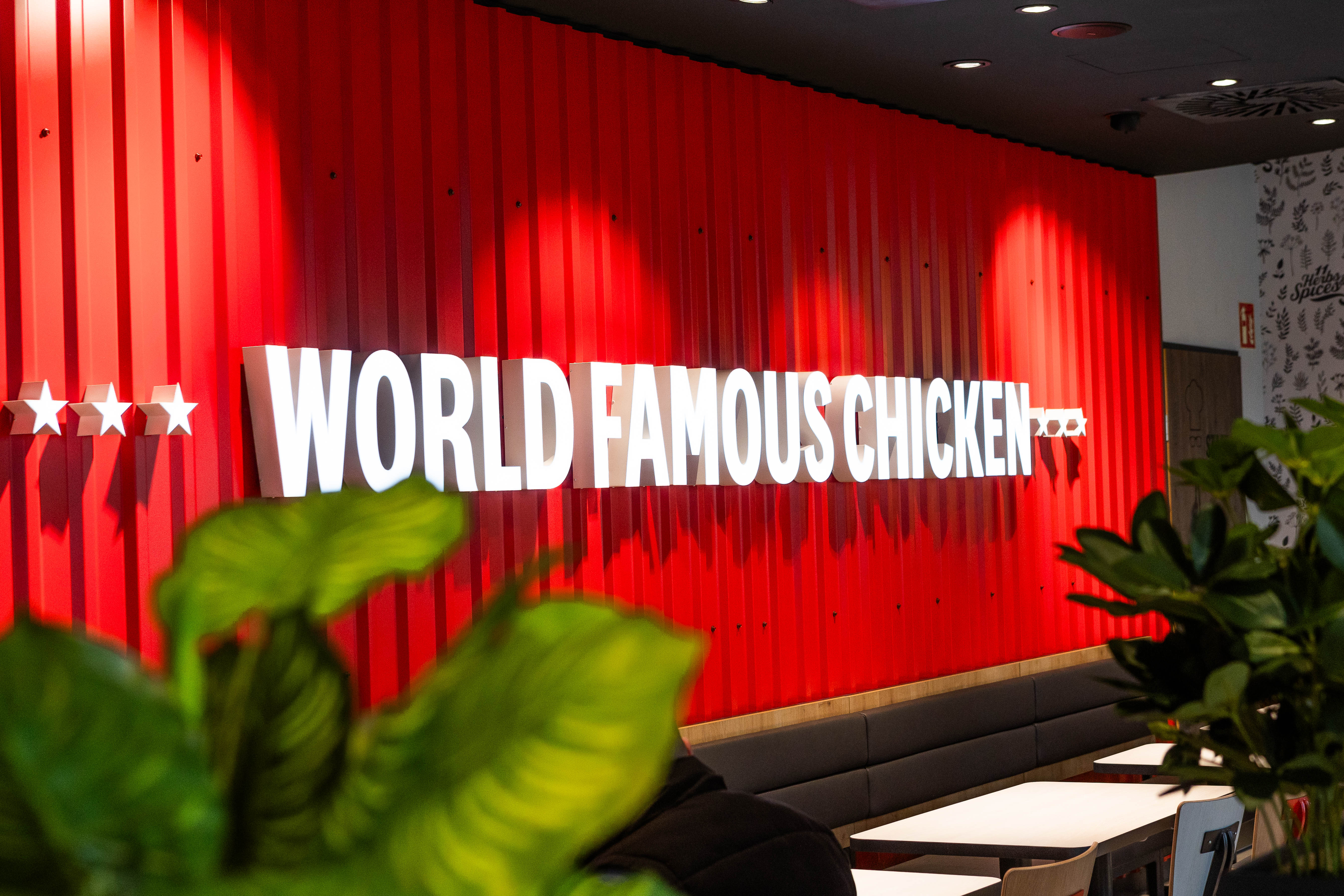 Rote Wand mit Leuchtschriftzug 'World Famous Chicken' im Restaurant der KFC-Filiale St. Pölten