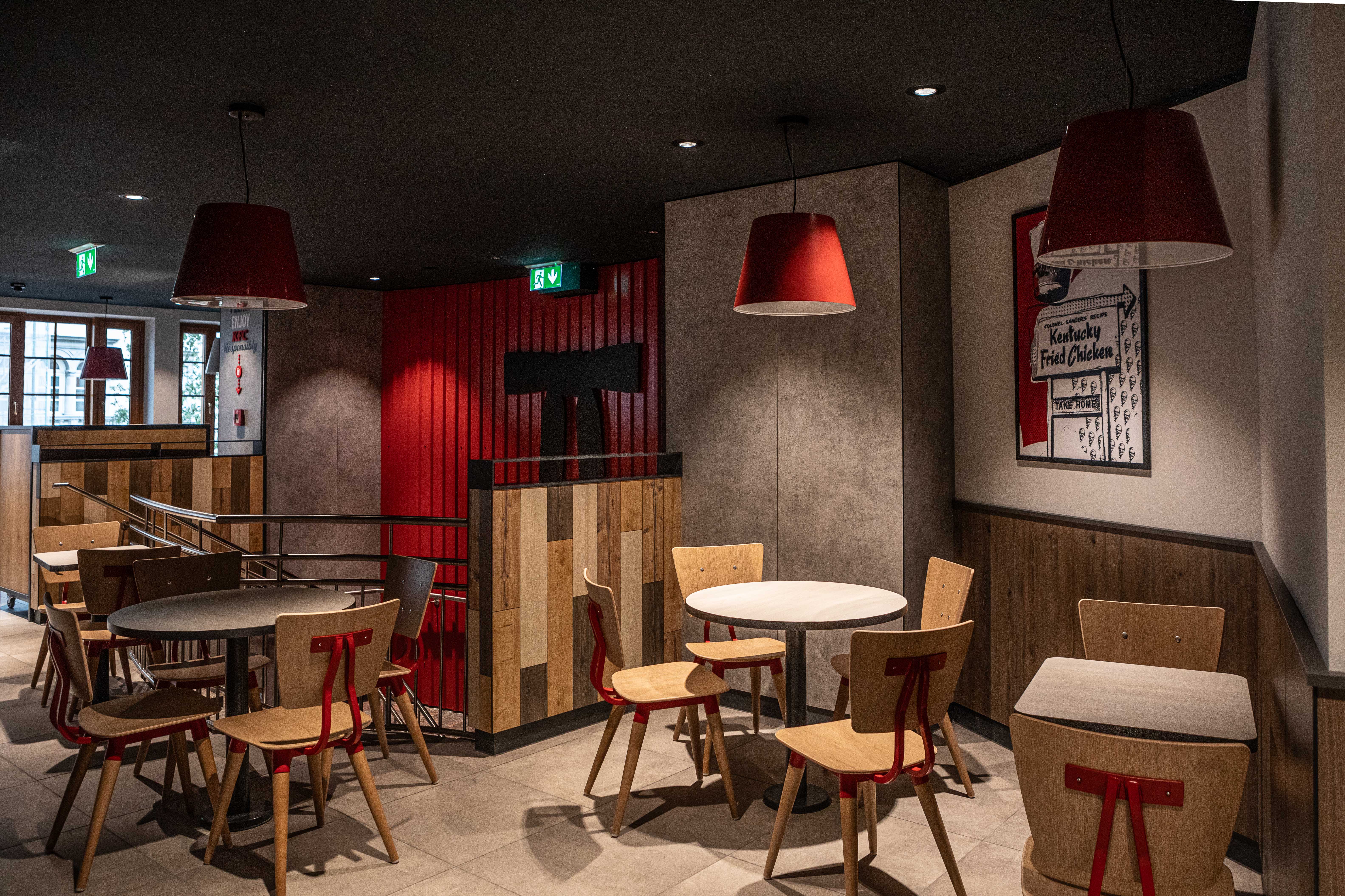 Sitzbereich der KFC-Filiale Villach mit roten Hängelampen und Holztischen
