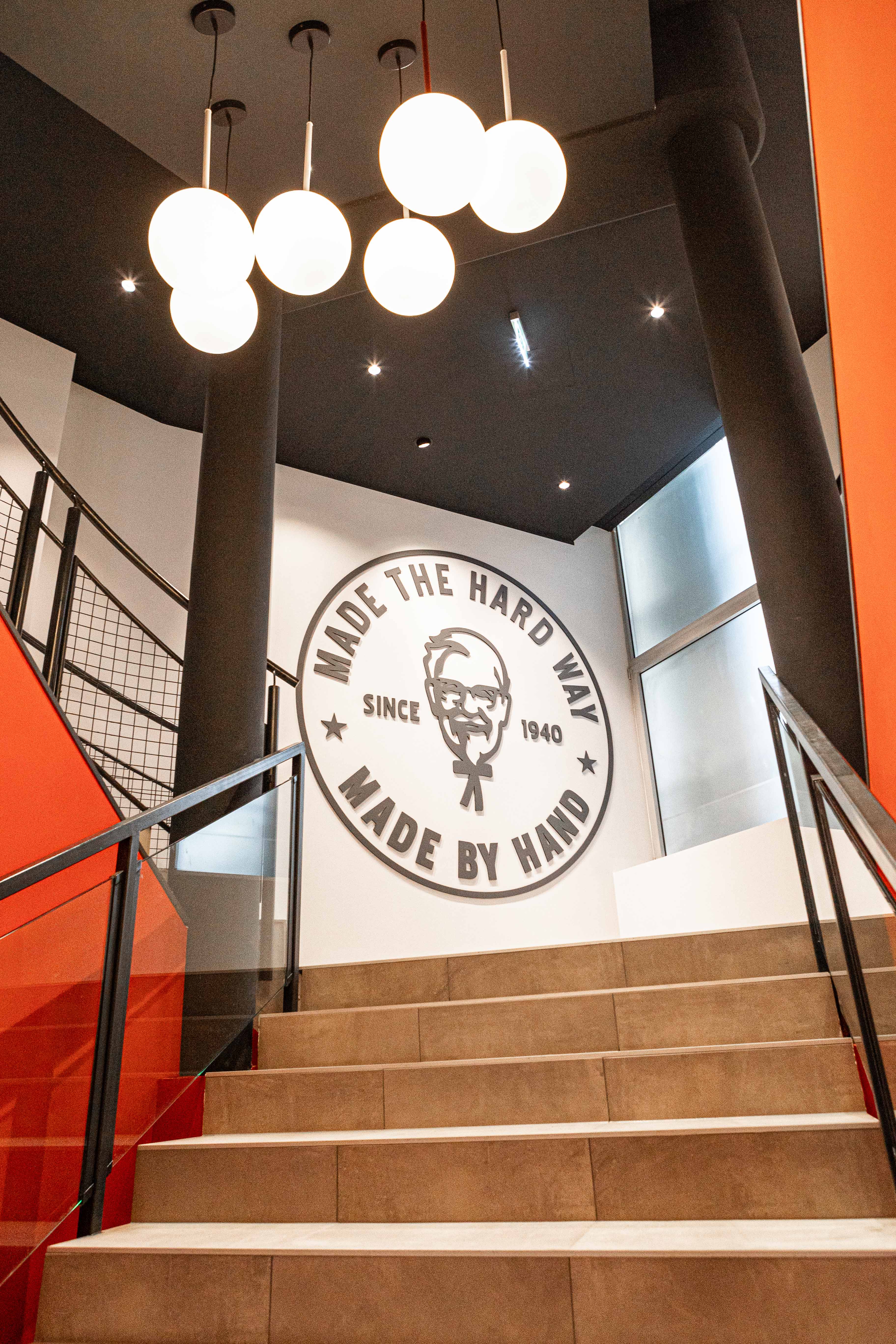 Treppenaufgang der KFC-Filiale St. Pölten mit Wandbild 'Made the Hard Way, Made by Hand'