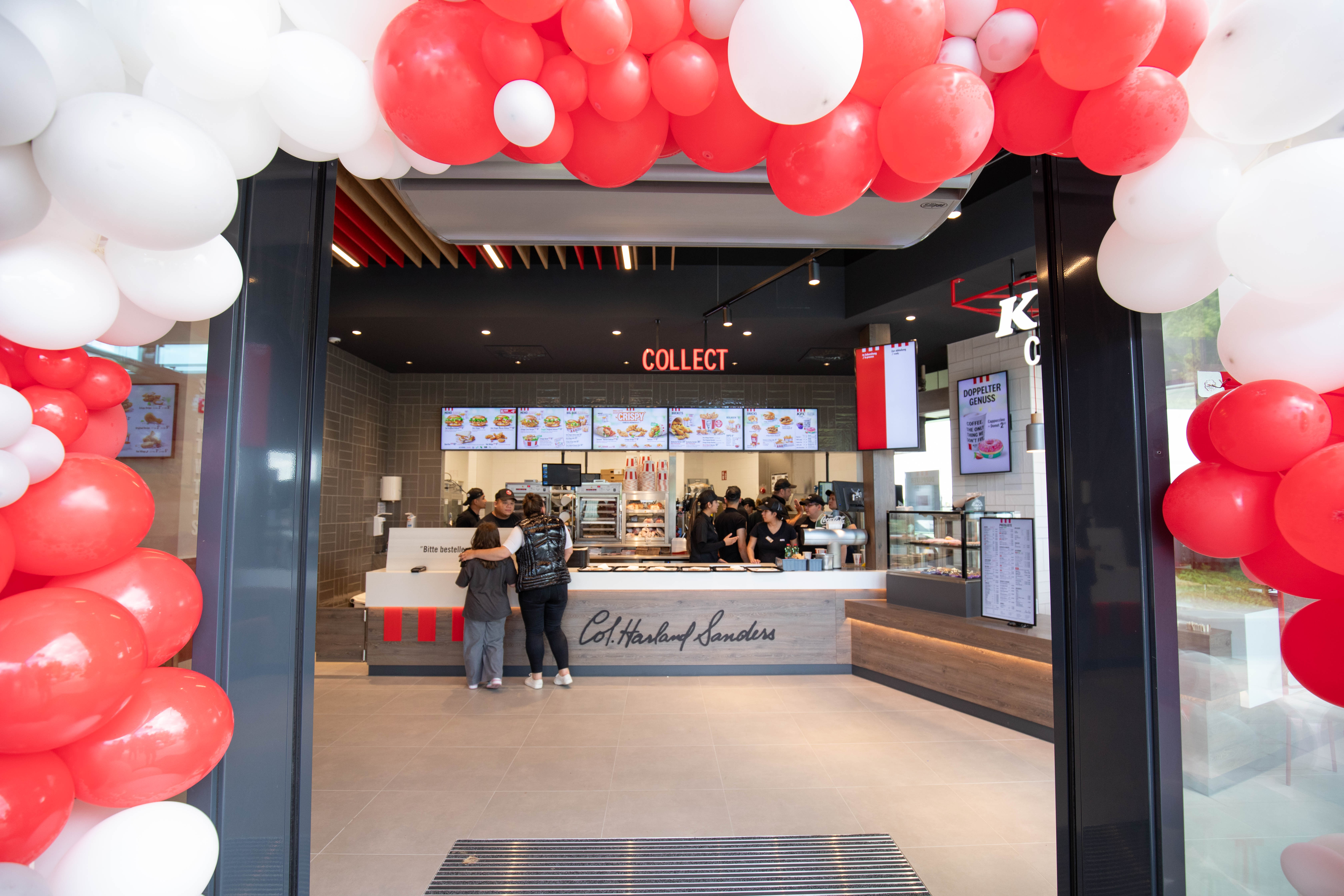 Eingang der KFC-Filiale Wels mit Ballonbogen und Blick zur Bestelltheke