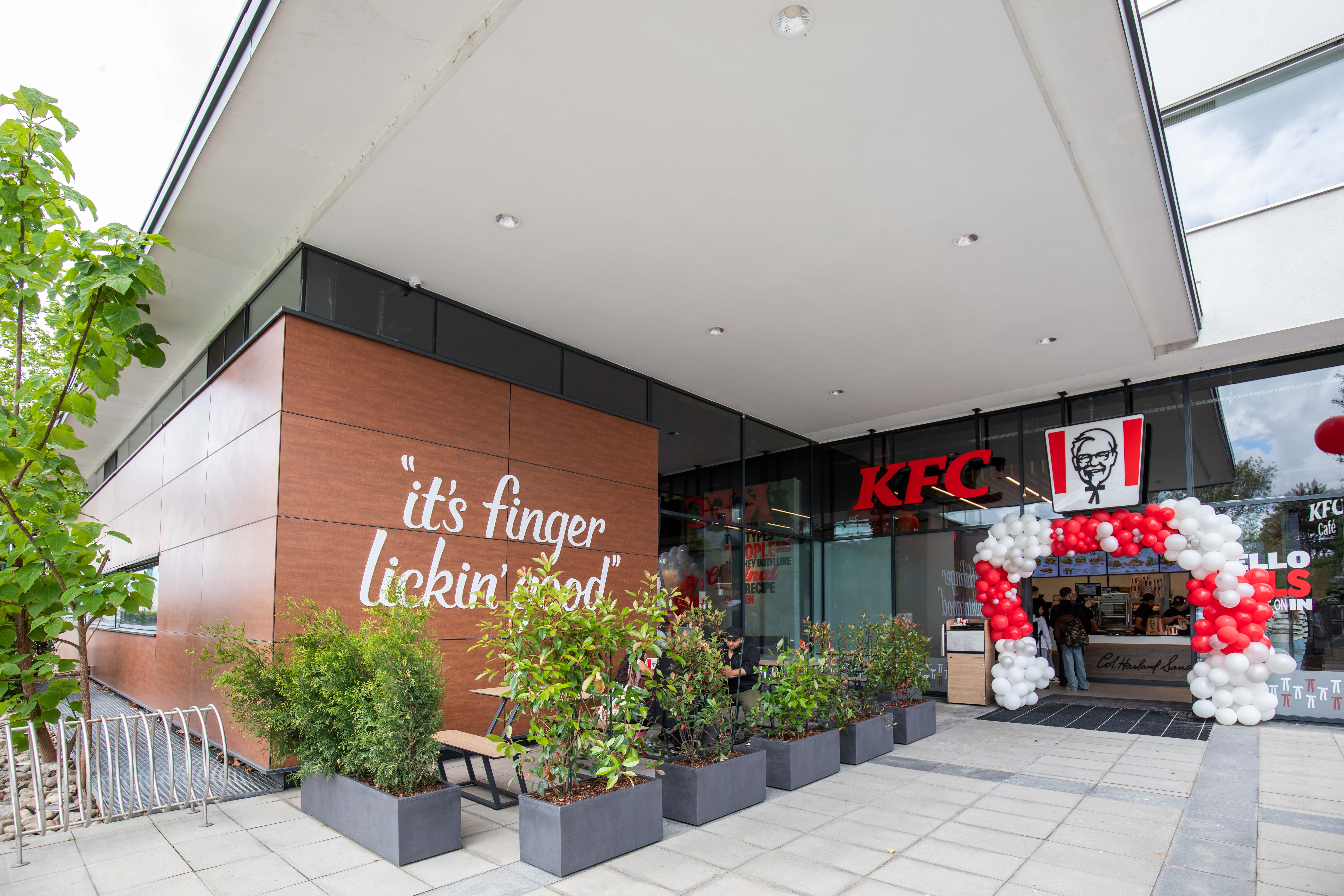 Außenfassade der KFC-Filiale Wels mit Schriftzug „it's finger lickin' good“ und Ballondekoration
