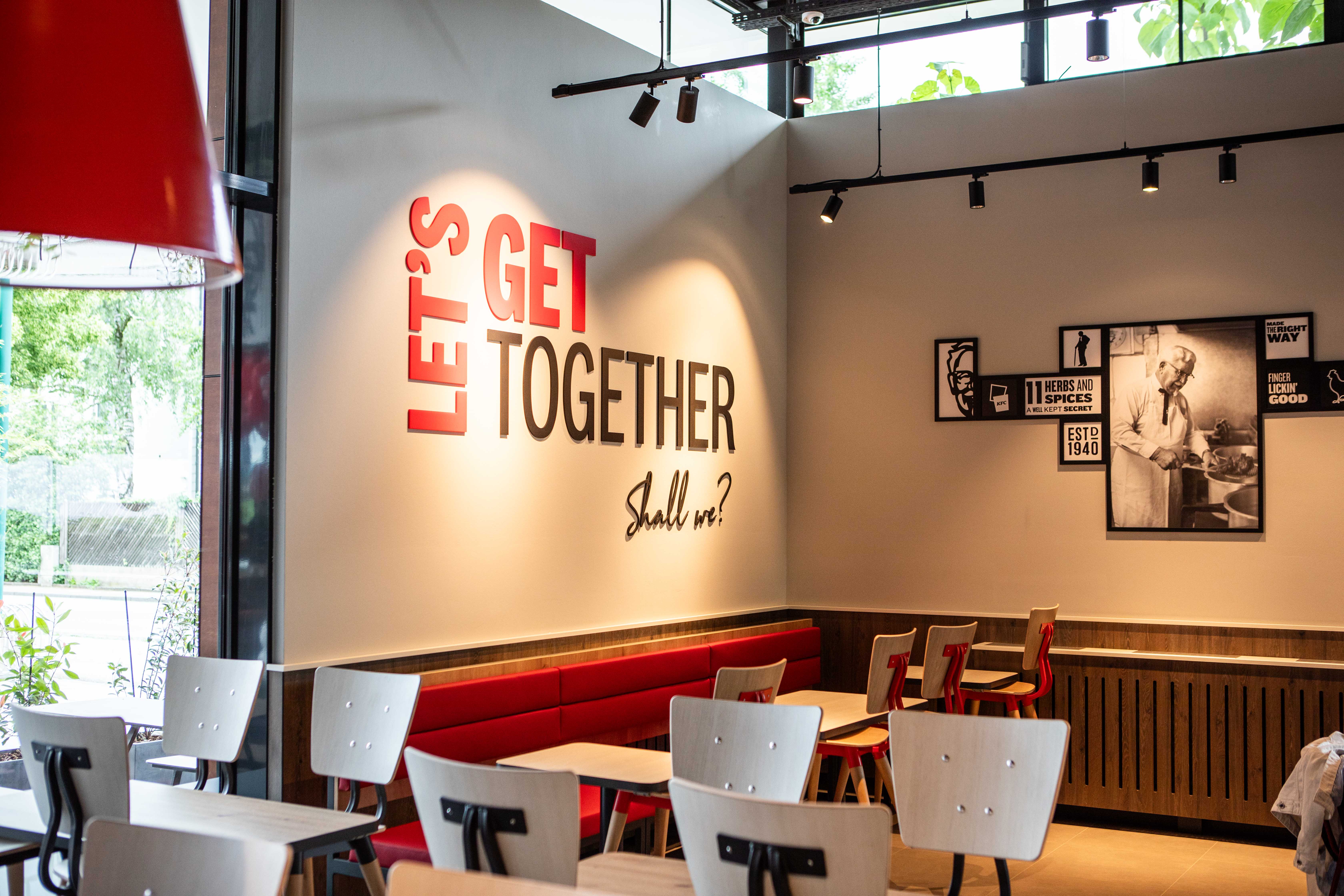 Innenraum der KFC-Filiale Wels mit Wandtext „Let's get together, shall we?“
