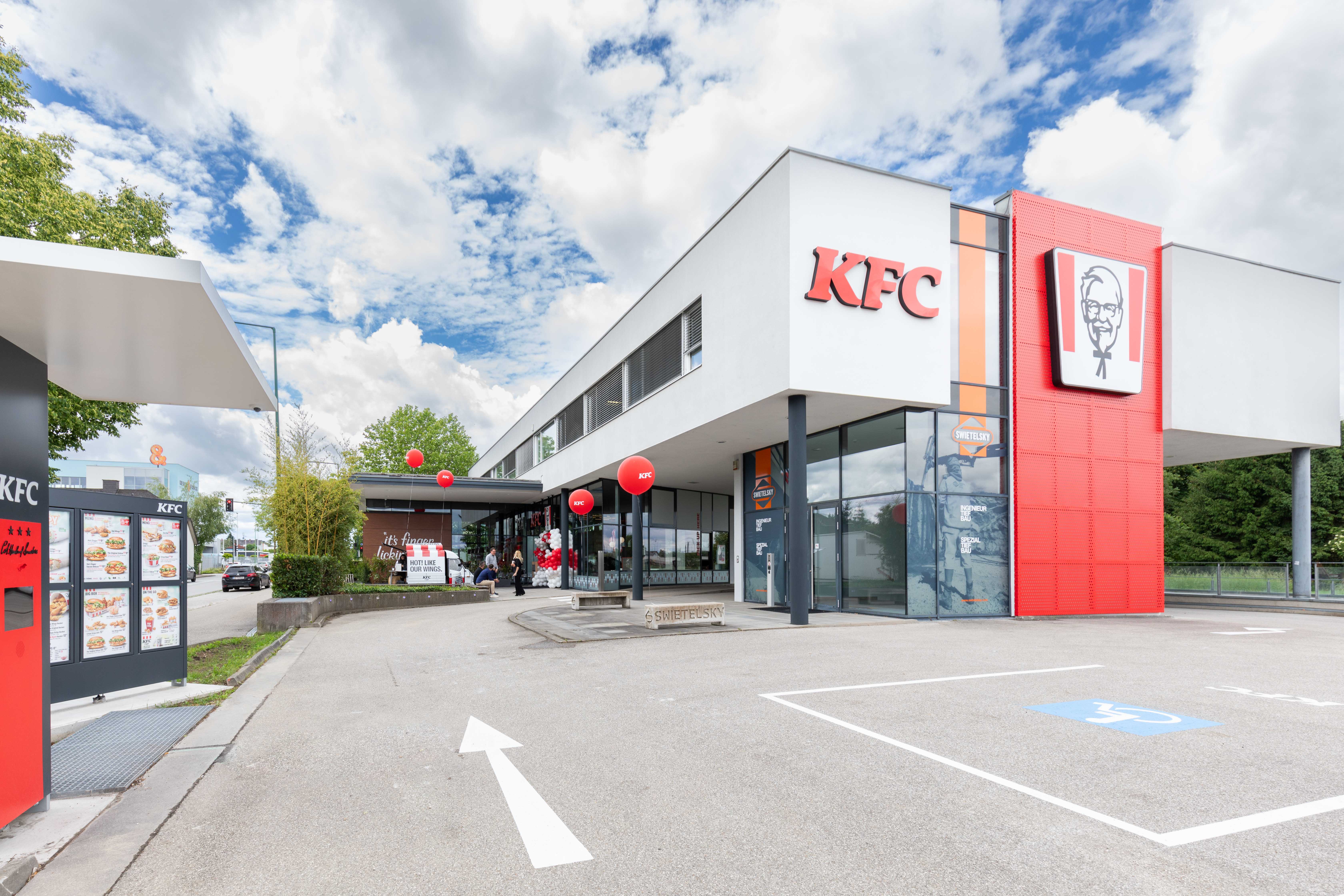 Außenansicht der KFC-Filiale Wels mit Drive-Thru-Bereich und Parkplatz