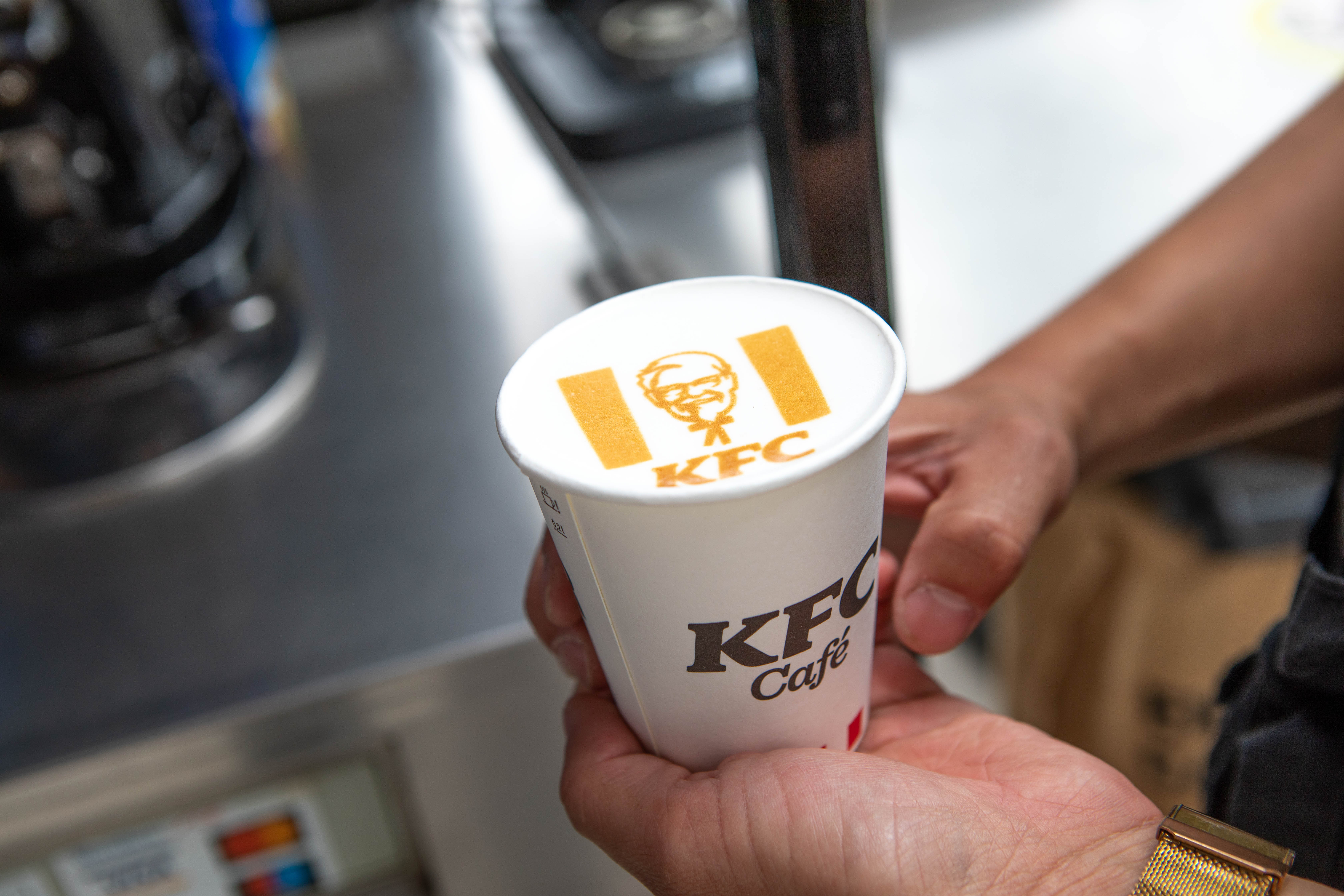 Hand hält Kaffeebecher der Marke KFC Café in der Filiale Wels