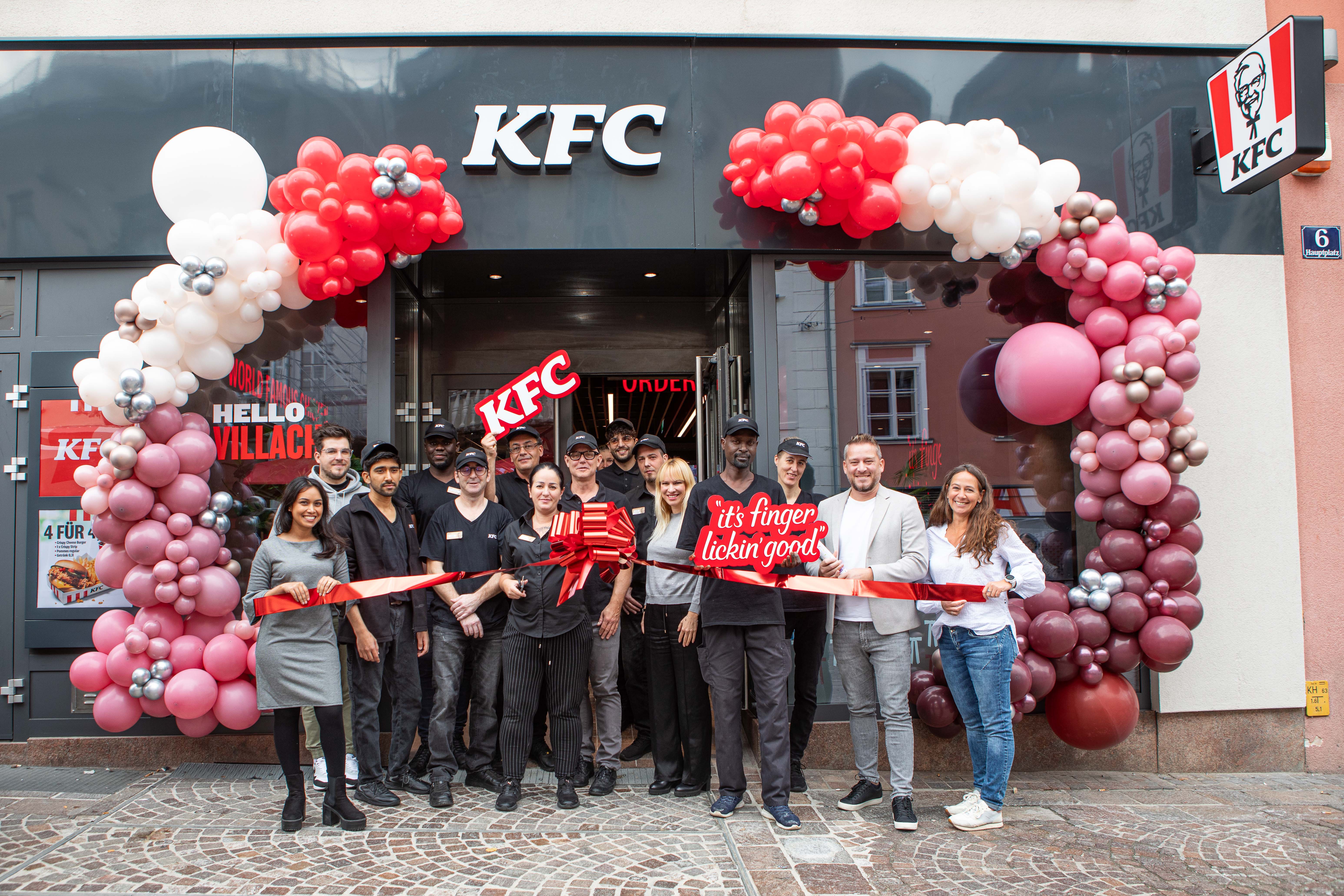 Eröffnung der KFC-Filiale Villach: Team und Gäste durchschneiden das Band vor dem Eingang