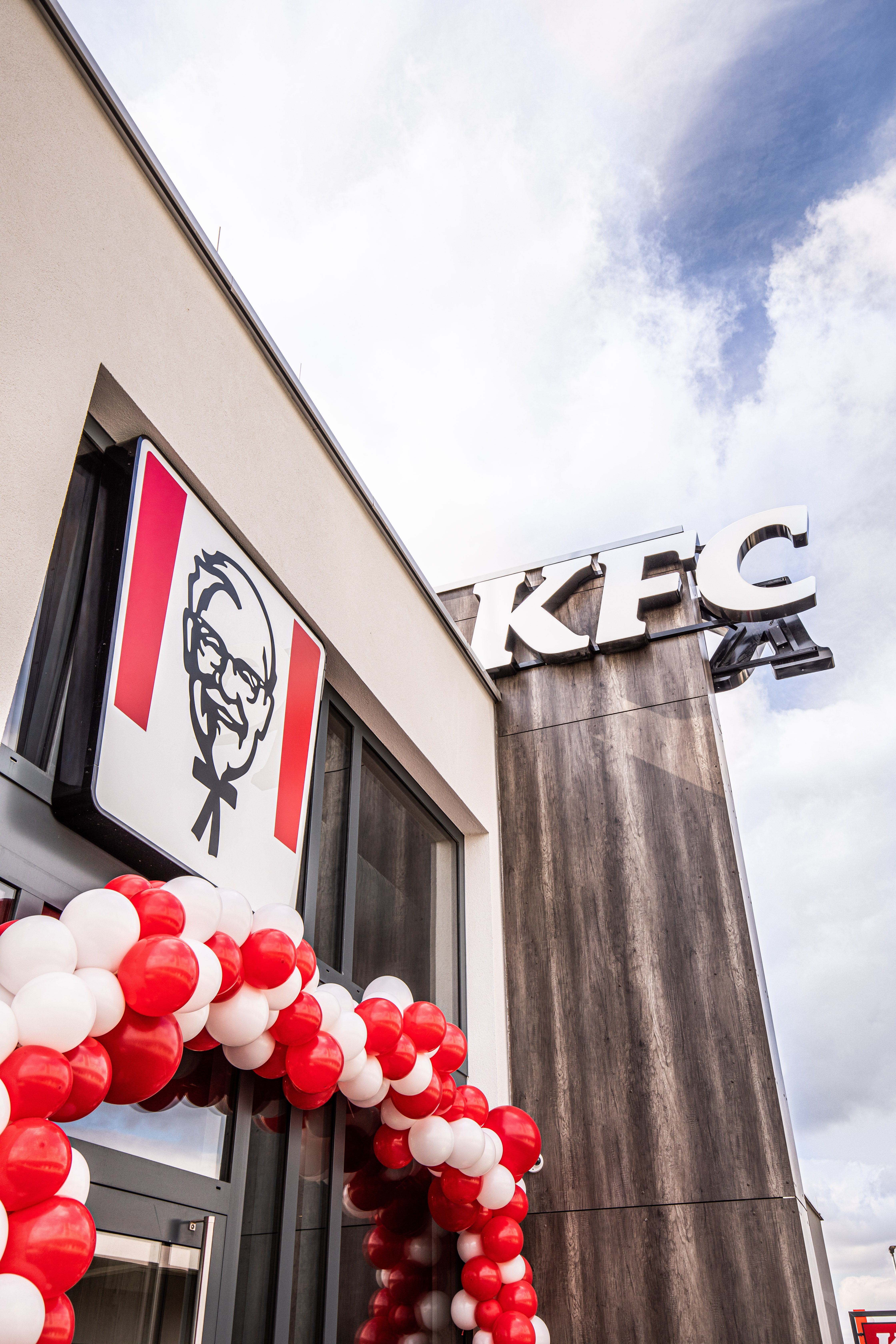 KFC-Logo an der Fassade der Filiale Parndorf mit roten und weißen Luftballons zur Eröffnung