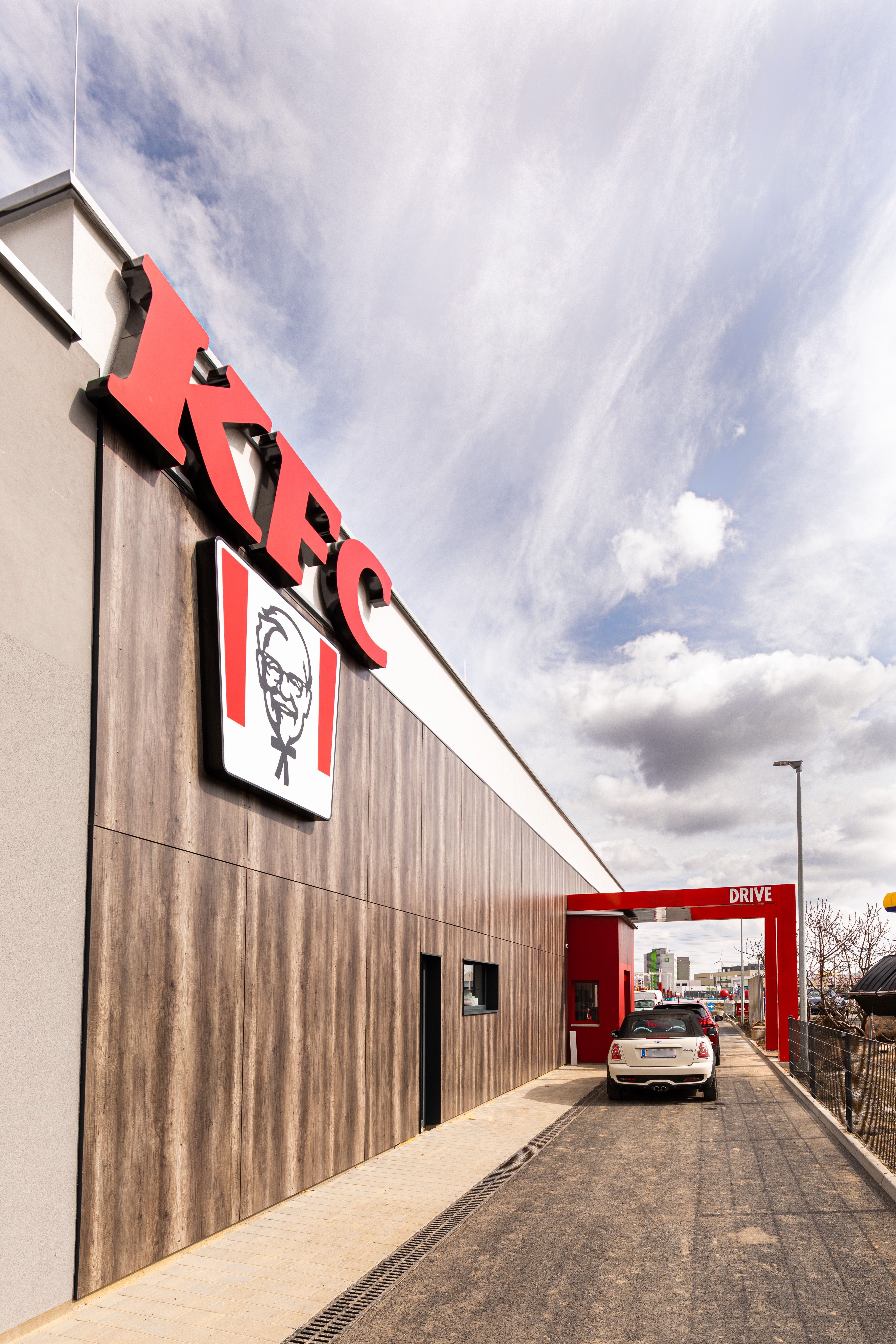 Außenfassade der KFC-Filiale Parndorf mit Logo und Einfahrt zum Drive-through