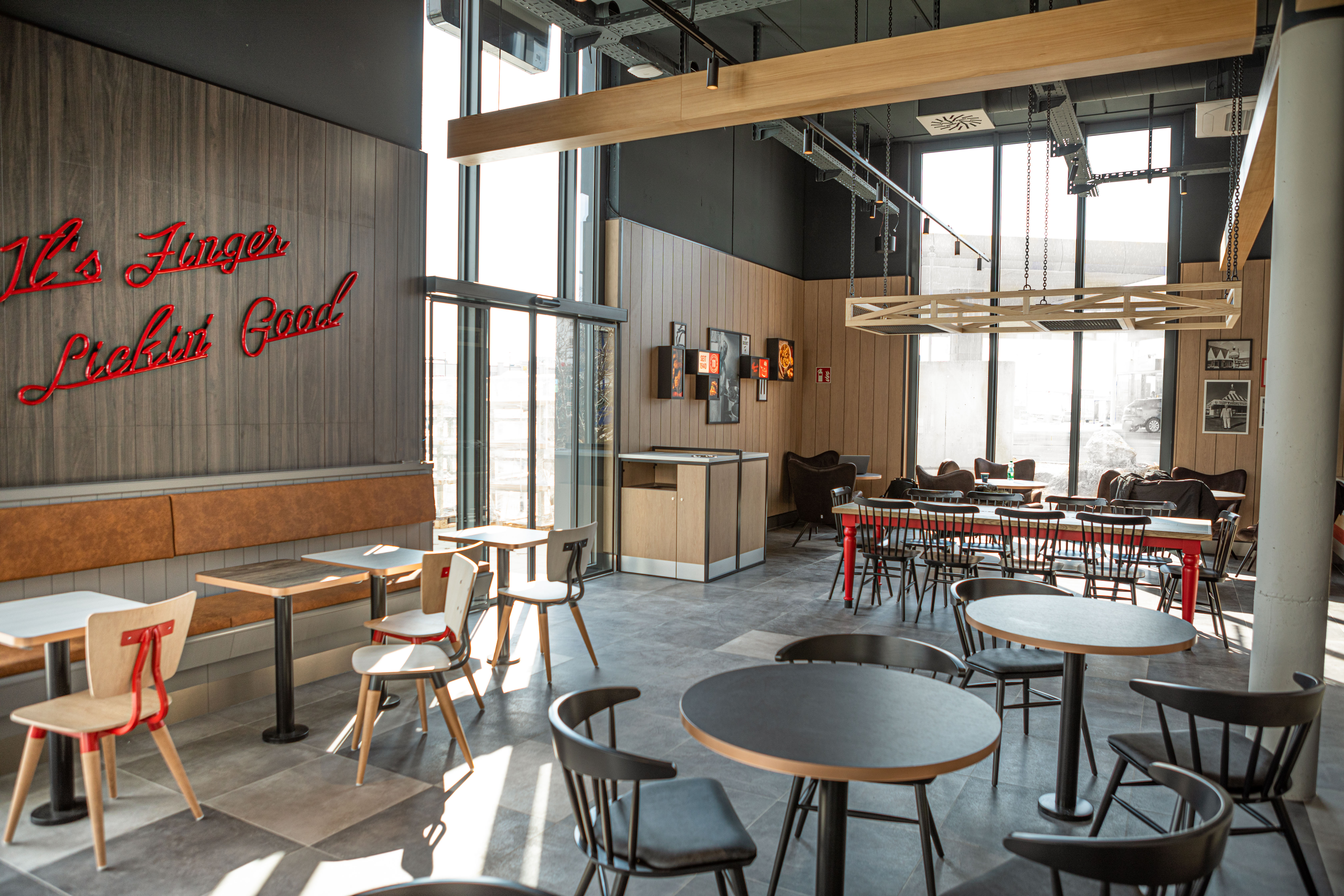 Sitzbereich der KFC-Filiale Parndorf mit rotem Leuchtschriftzug 'It's Finger Lickin' Good'