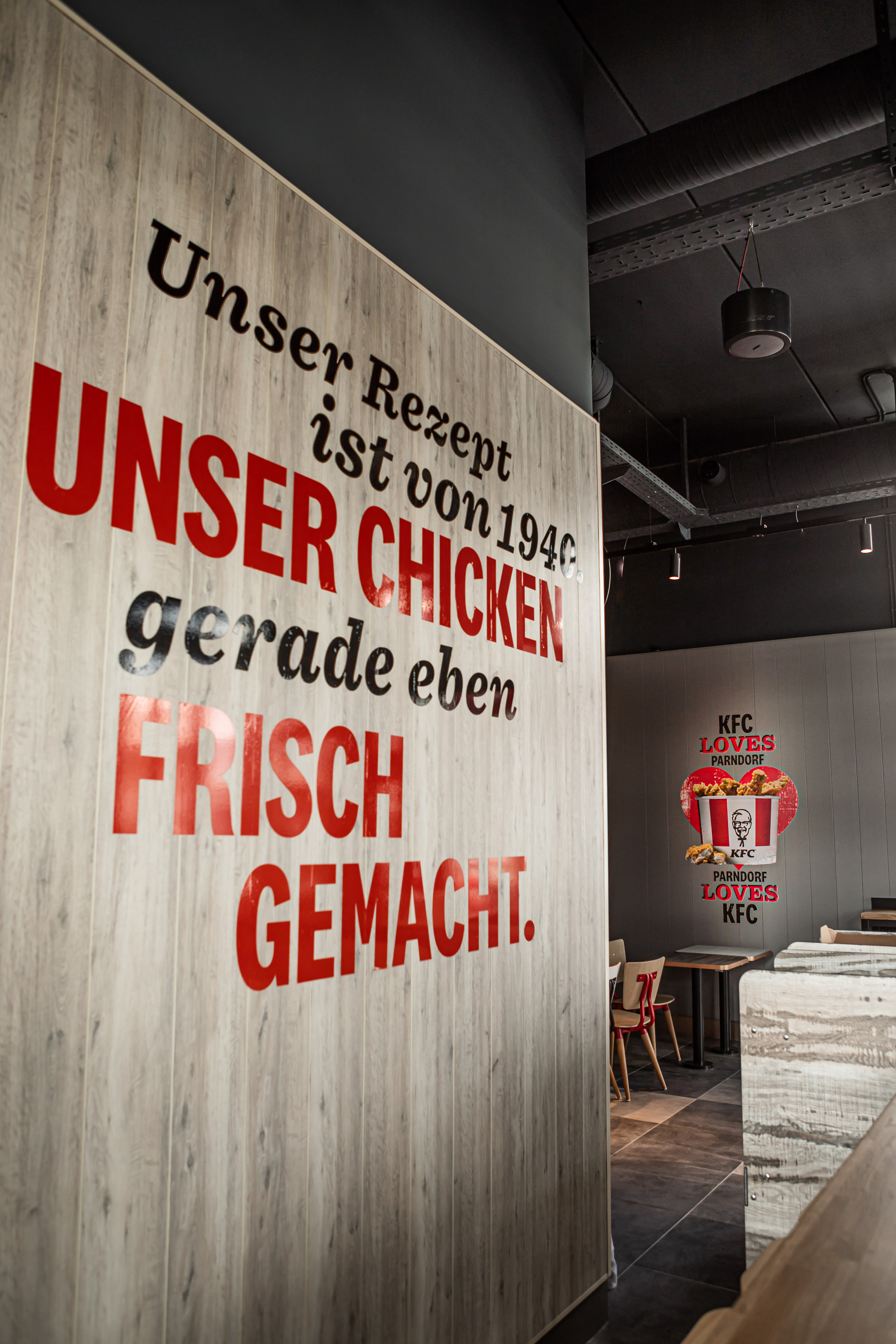 Wandtext 'Unser Chicken frisch gemacht' und KFC-Logo im Gastraum der Filiale Parndorf
