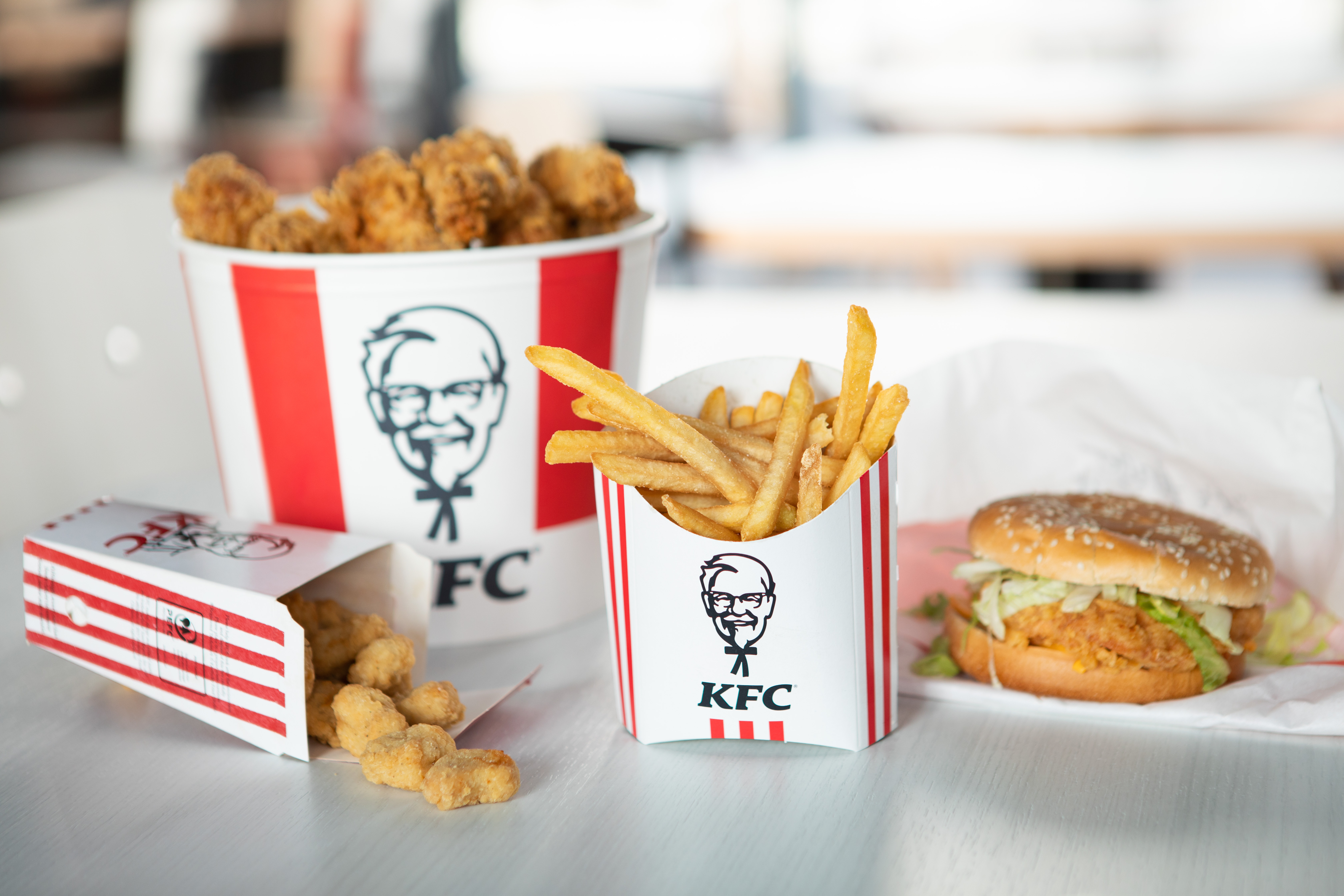 KFC-Bucket mit Chicken, Pommes und Burger als Produktfoto auf hellem Untergrund