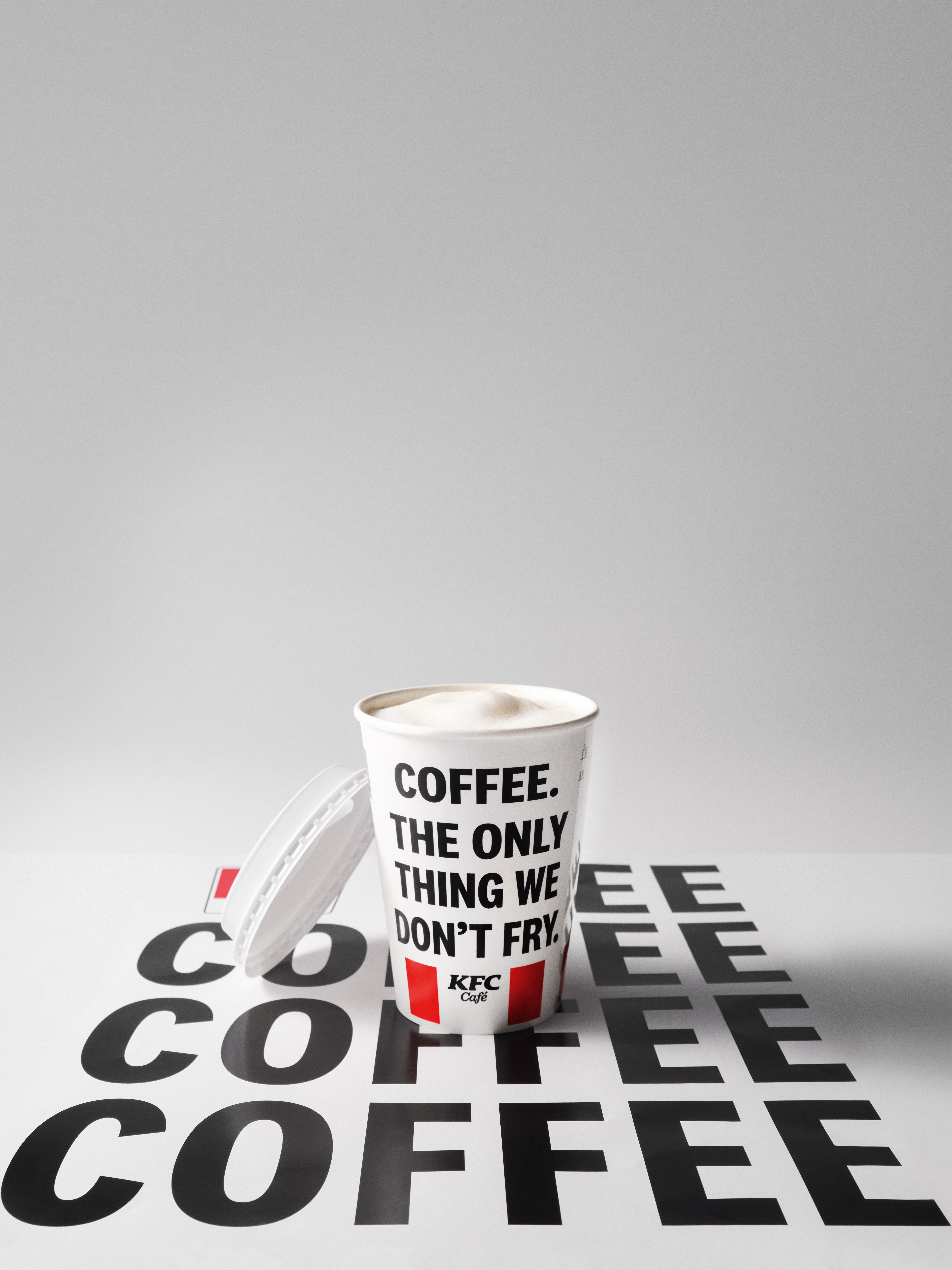 KFC-Café-Kaffeebecher auf einer Fläche mit wiederholtem Schriftzug 'Coffee'