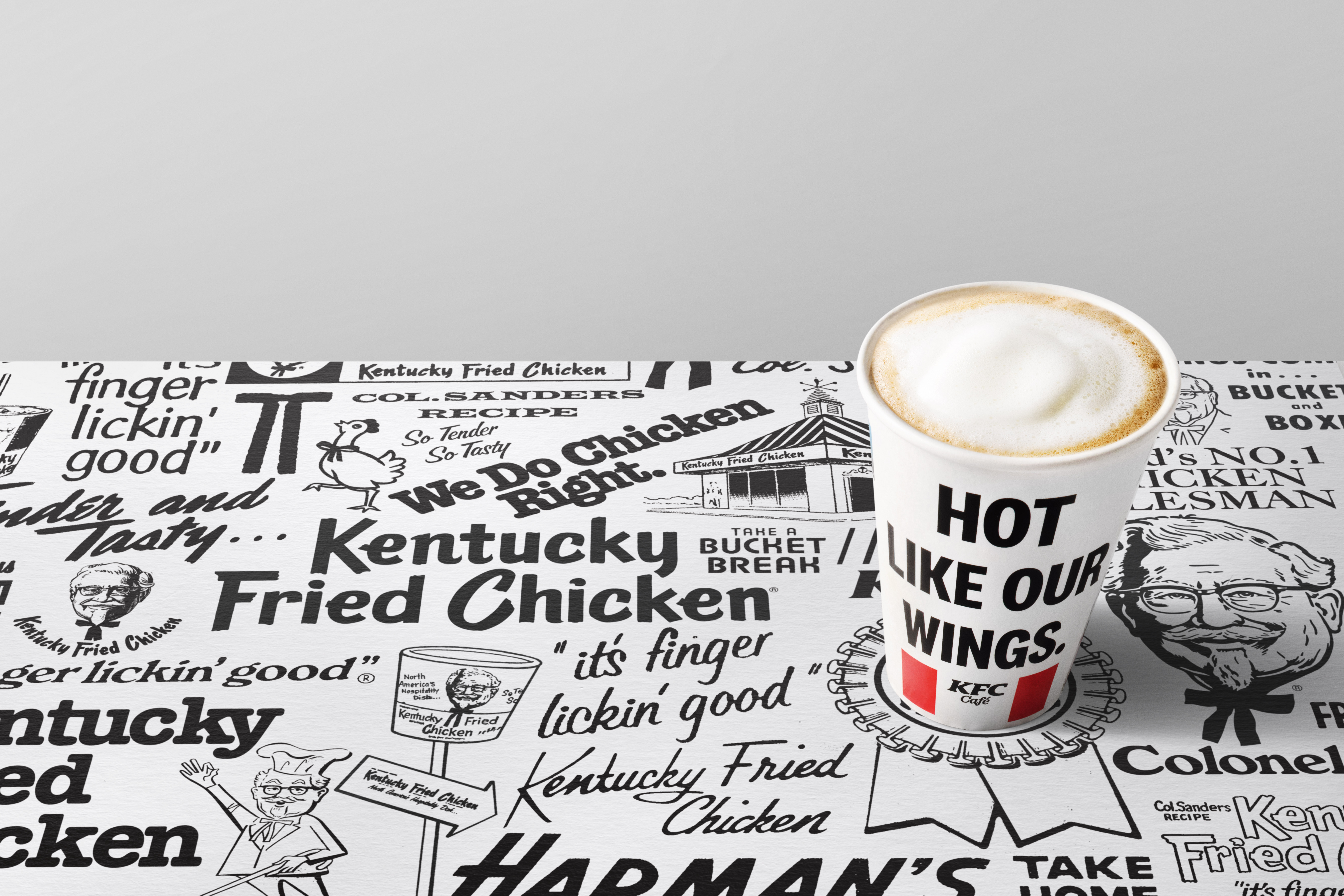KFC-Café-Kaffeebecher 'Hot Like Our Wings' auf bedruckter Unterlage mit KFC-Motiven