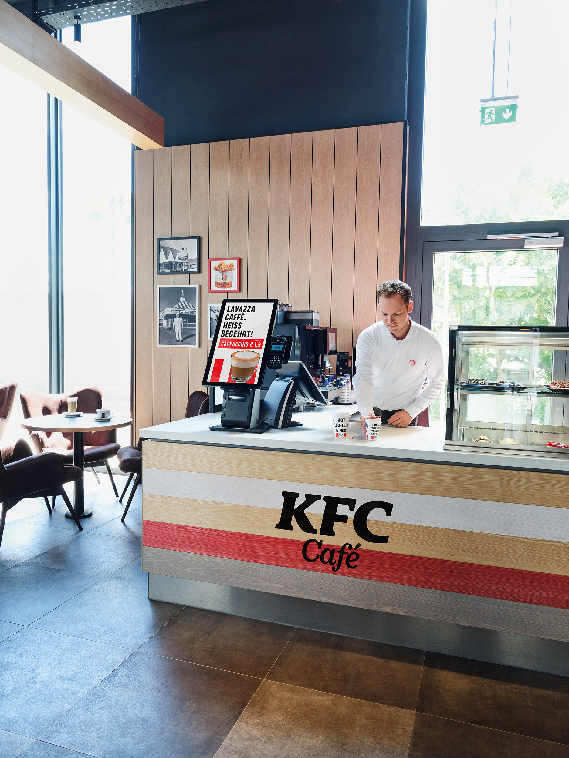 KFC-Café-Theke mit Mitarbeiter an der Kaffeemaschine und Sitzbereich im Hintergrund