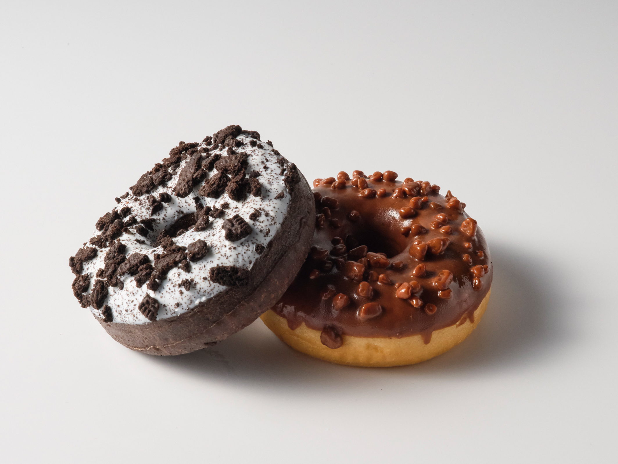 Zwei KFC-Donuts, einer mit Keksstreuseln, einer mit Schokoglasur und Krokant