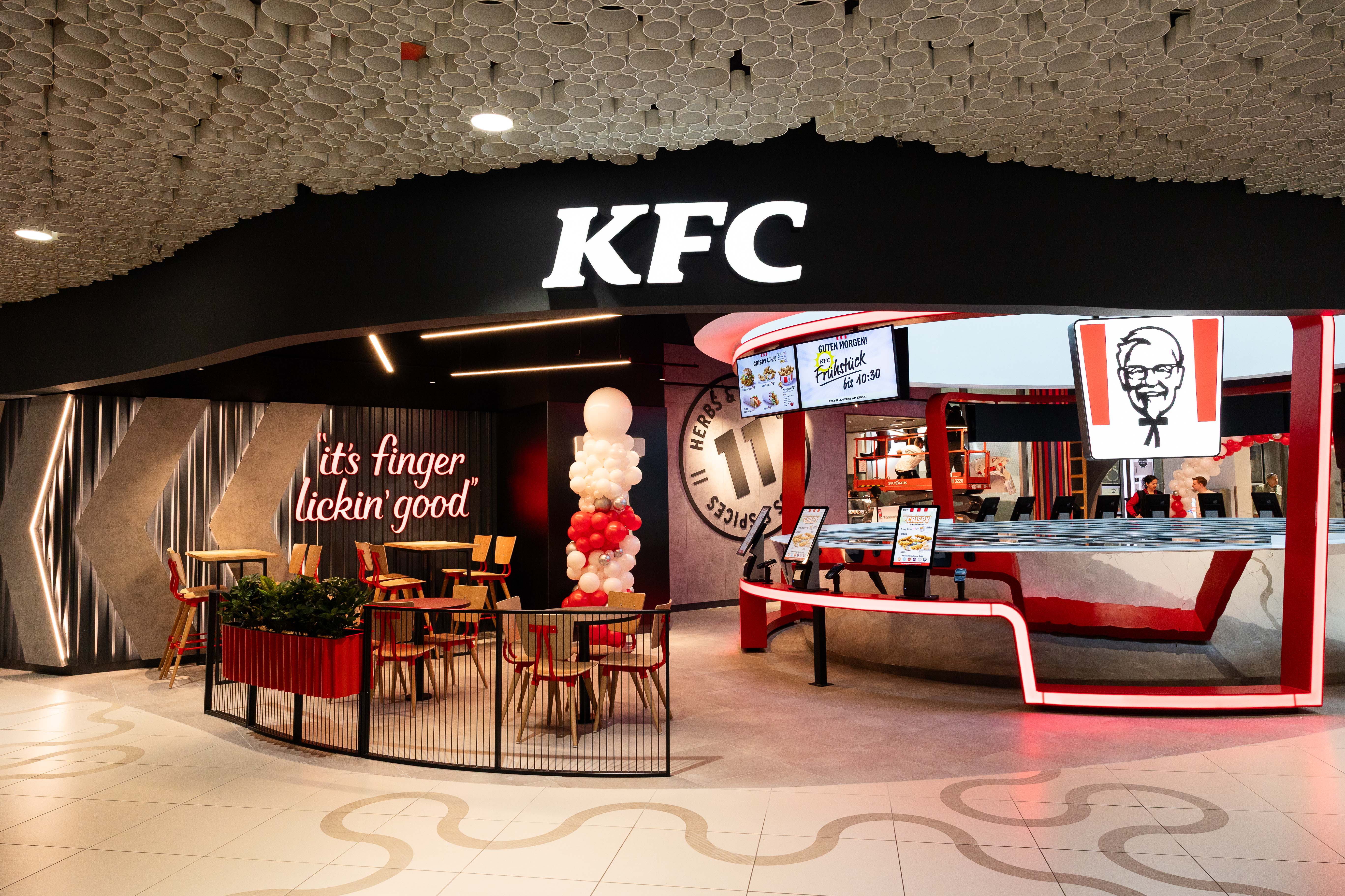 Eingangsbereich der KFC-Filiale Wien Mitte mit Sitzecke und Schriftzug 'It's Finger Lickin' Good'