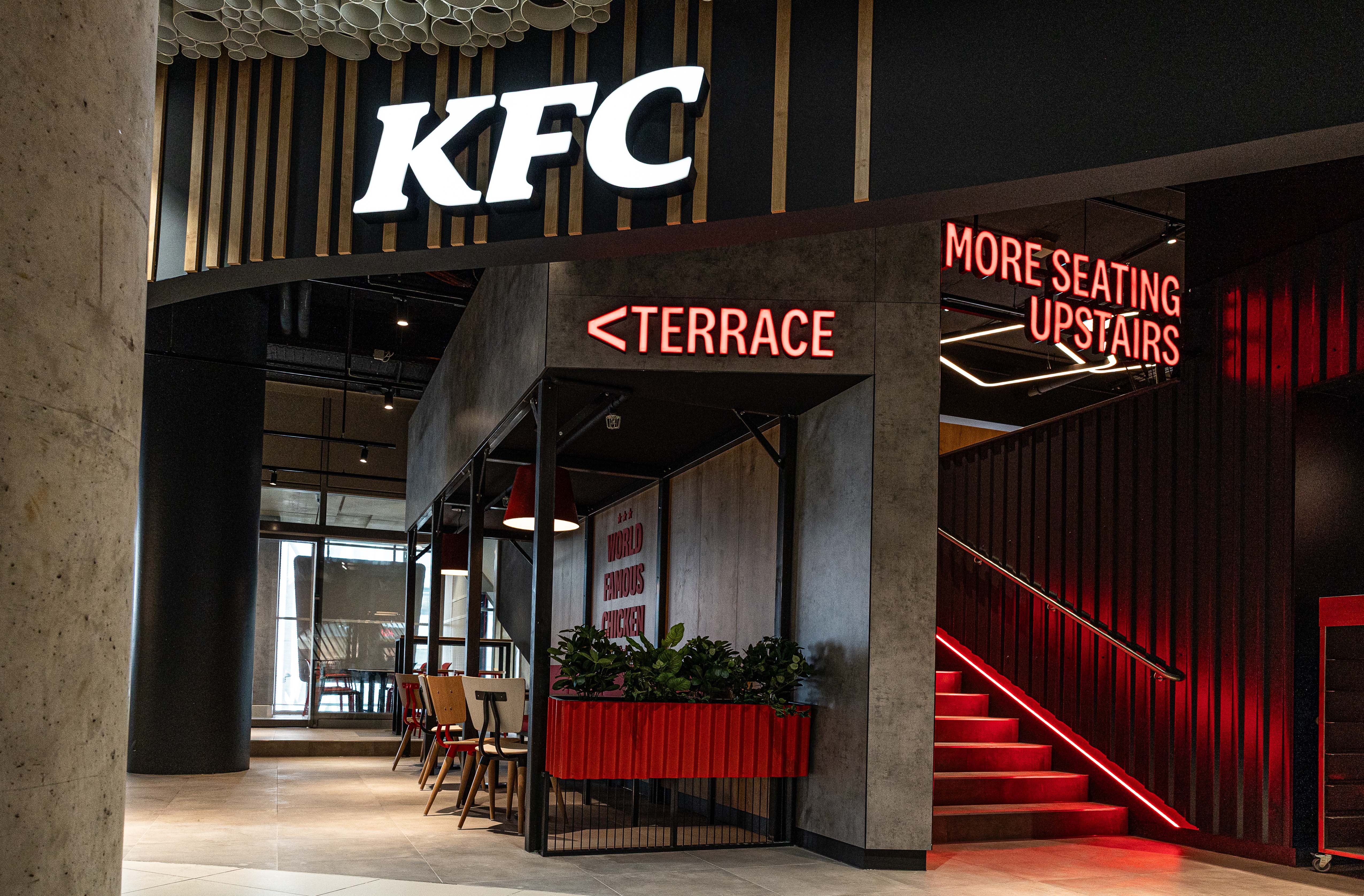 Eingangsbereich der KFC-Filiale Wien Mitte mit Hinweis zur Terrasse und roter Treppe nach oben