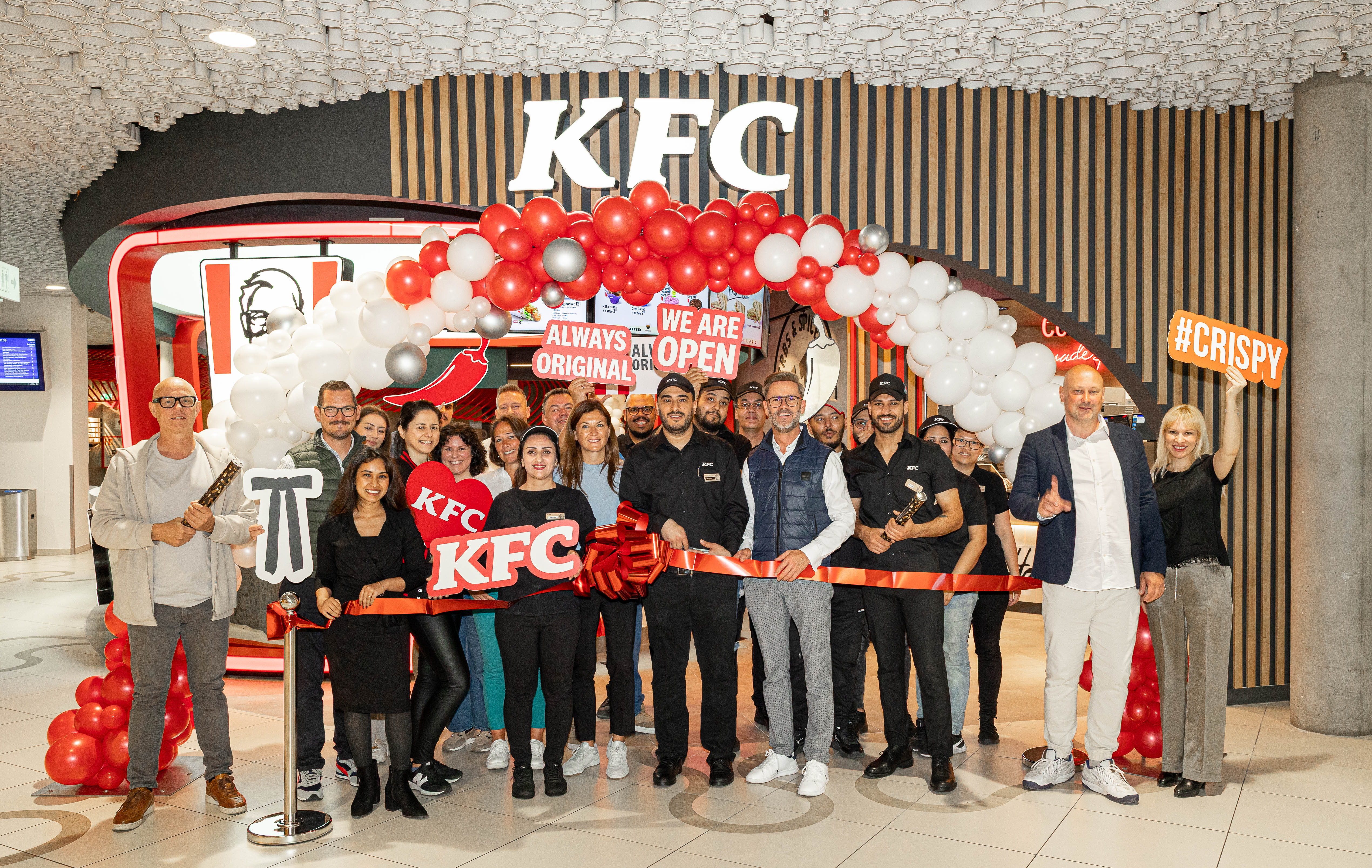 Eröffnungsfeier der KFC-Filiale Wien Mitte: Team und Gäste vor rot-weißer Ballondekoration