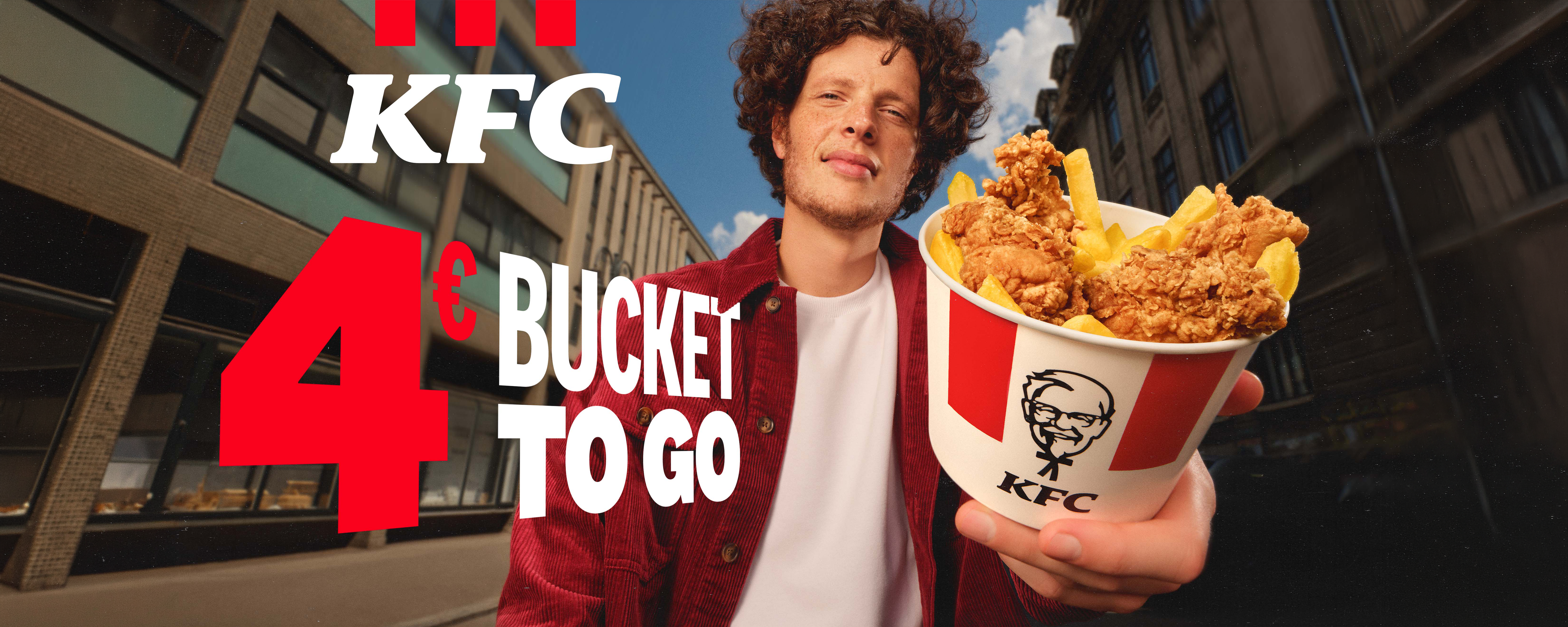 KFC 4€ Bucket to go: Mann mit Chicken-Bucket in der Stadt, Aktionsangebot zum Mitnehmen