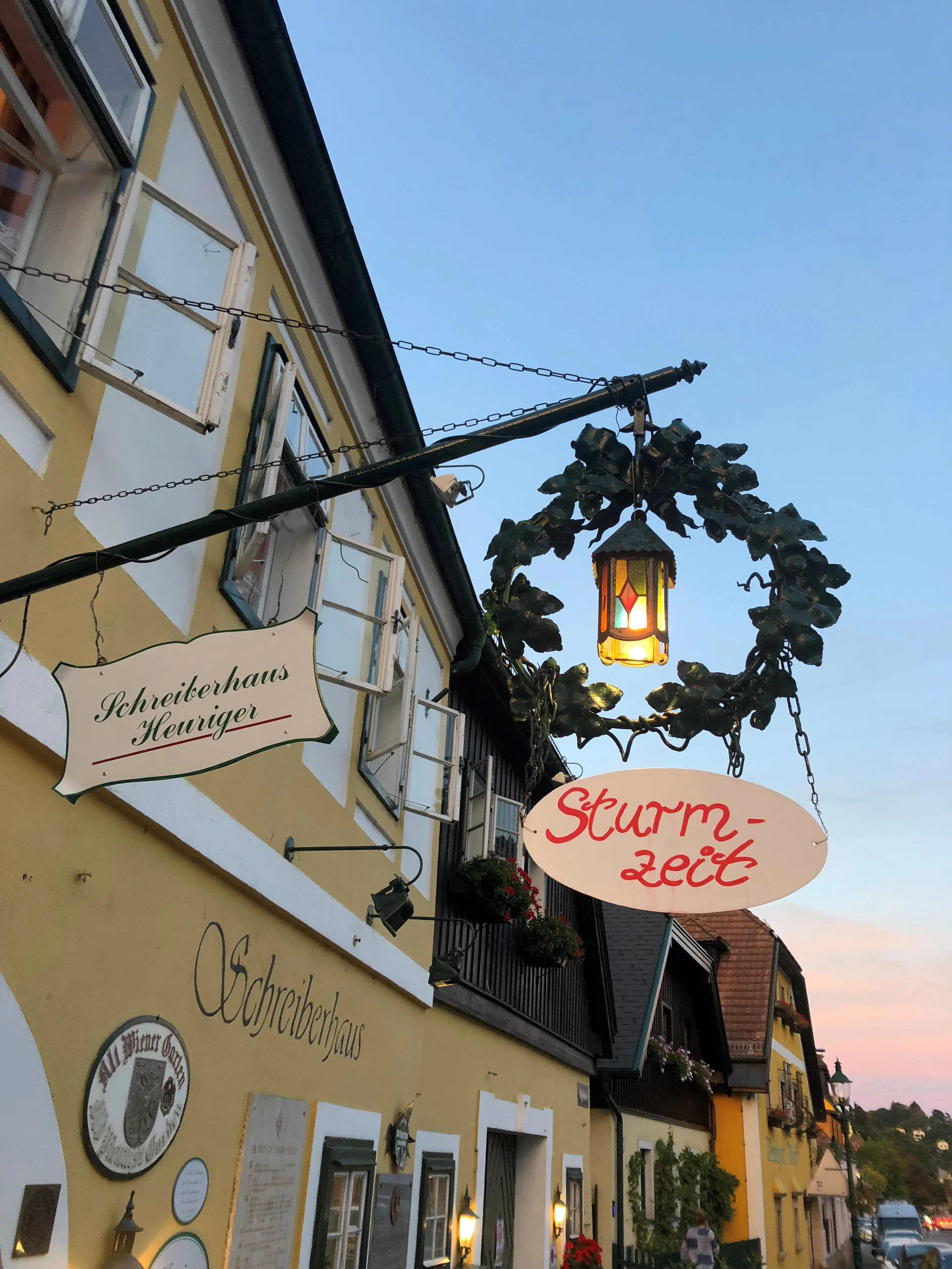 Historisches Schild des Schreiberhaus Heurigen mit der Aufschrift Sturmzeit in den Abendstunden.