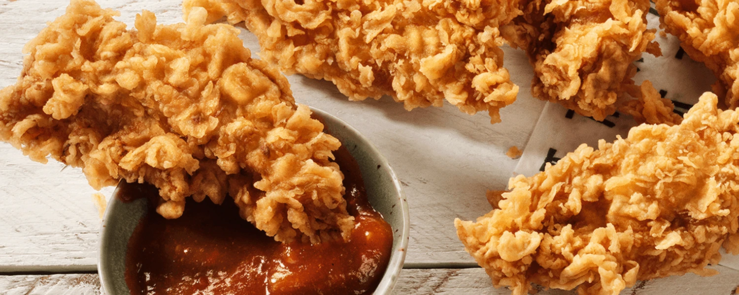Knusprige KFC Crispy Strips mit BBQ-Dip auf weissem Holztisch, Kopfbild der Qualitätsseite