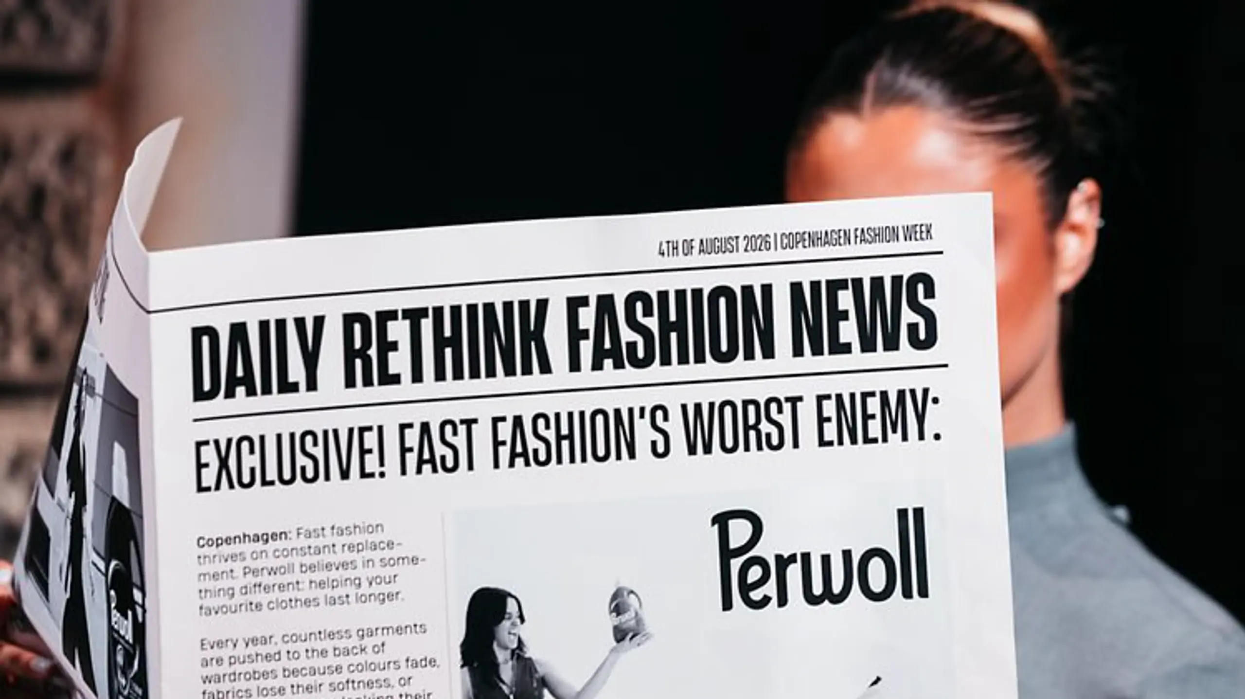 Frau liest eine Zeitung mit der Headline „Daily Rethink Fashion News“