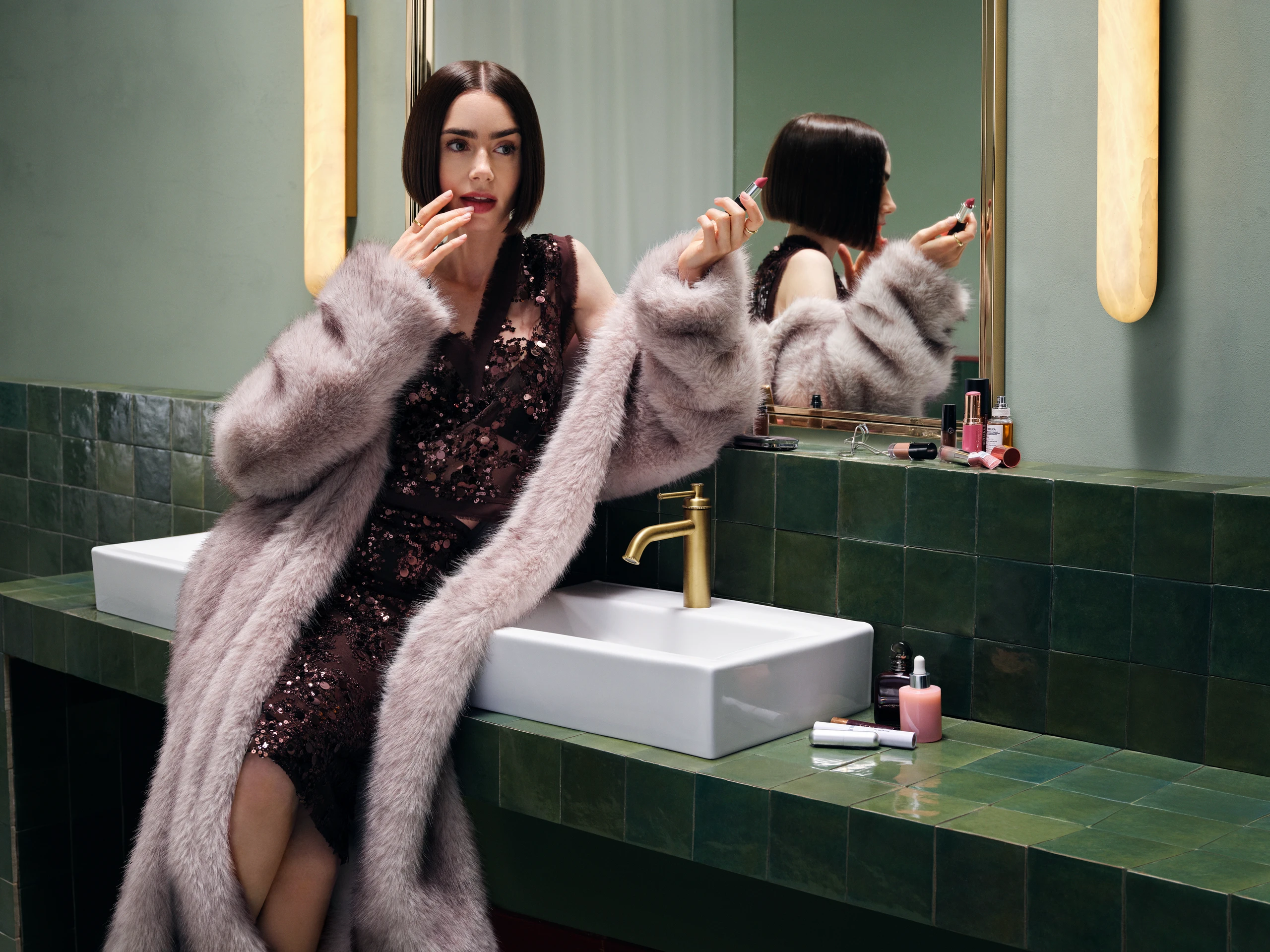 Lily Collins in Glitzerkleid und Fake Fur Mantel am Waschbecken