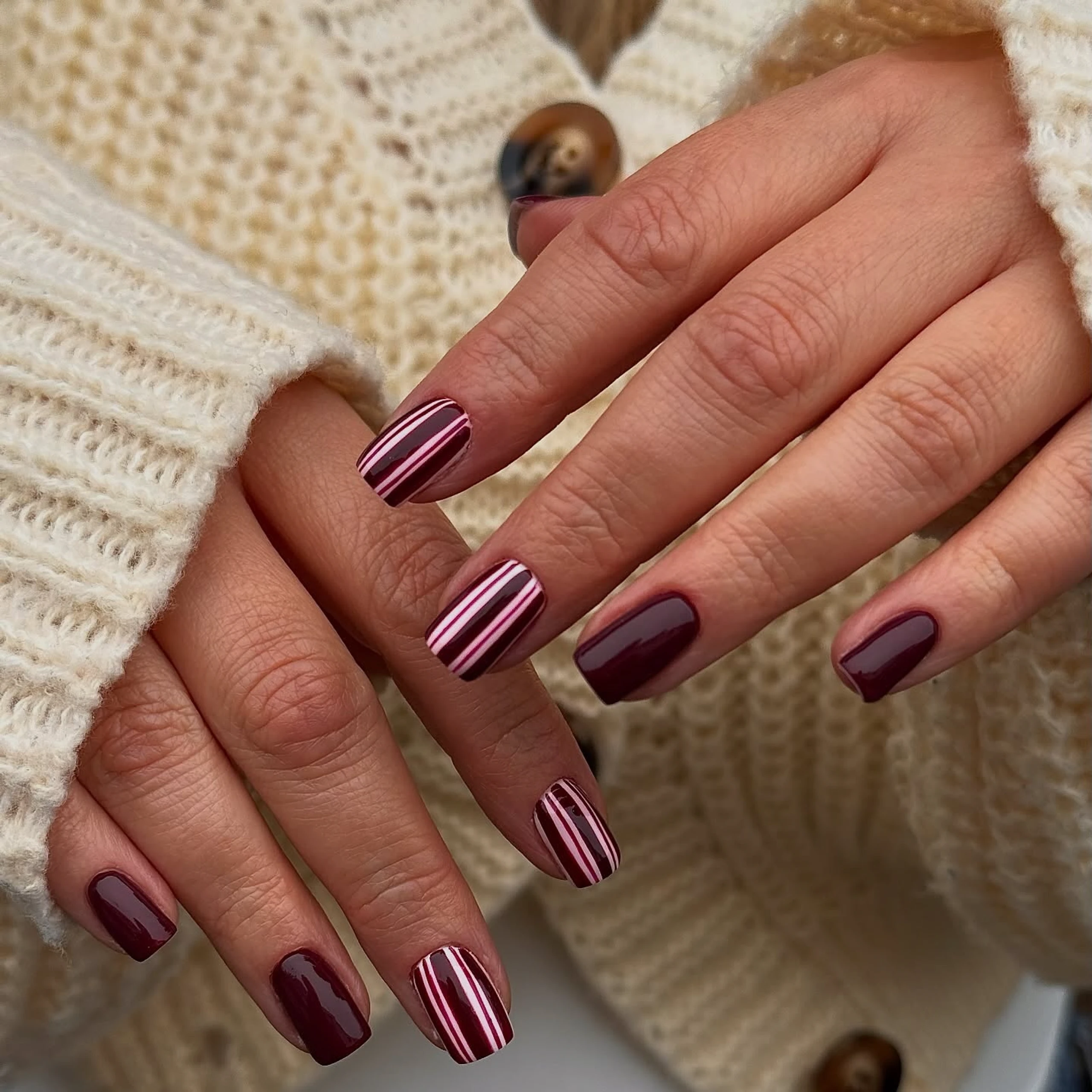 Close up von Nägeln mit Streifen in dunkelrot und hellrot und Rosa
