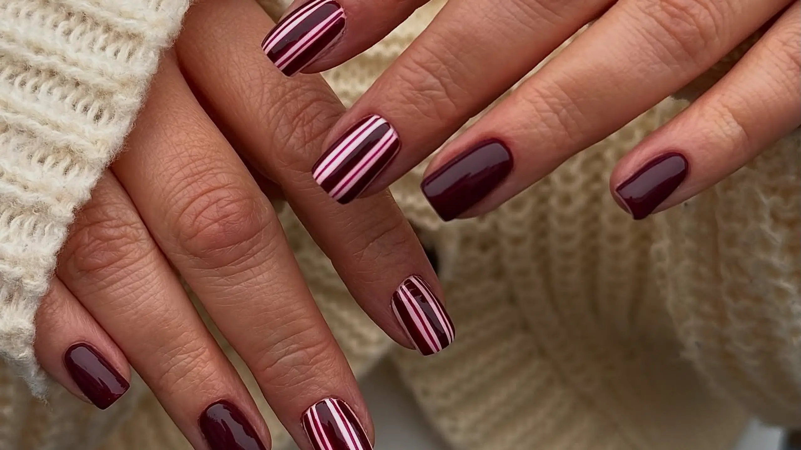 Close up von Nägeln mit Streifen in dunkelrot und hellrot und Rosa