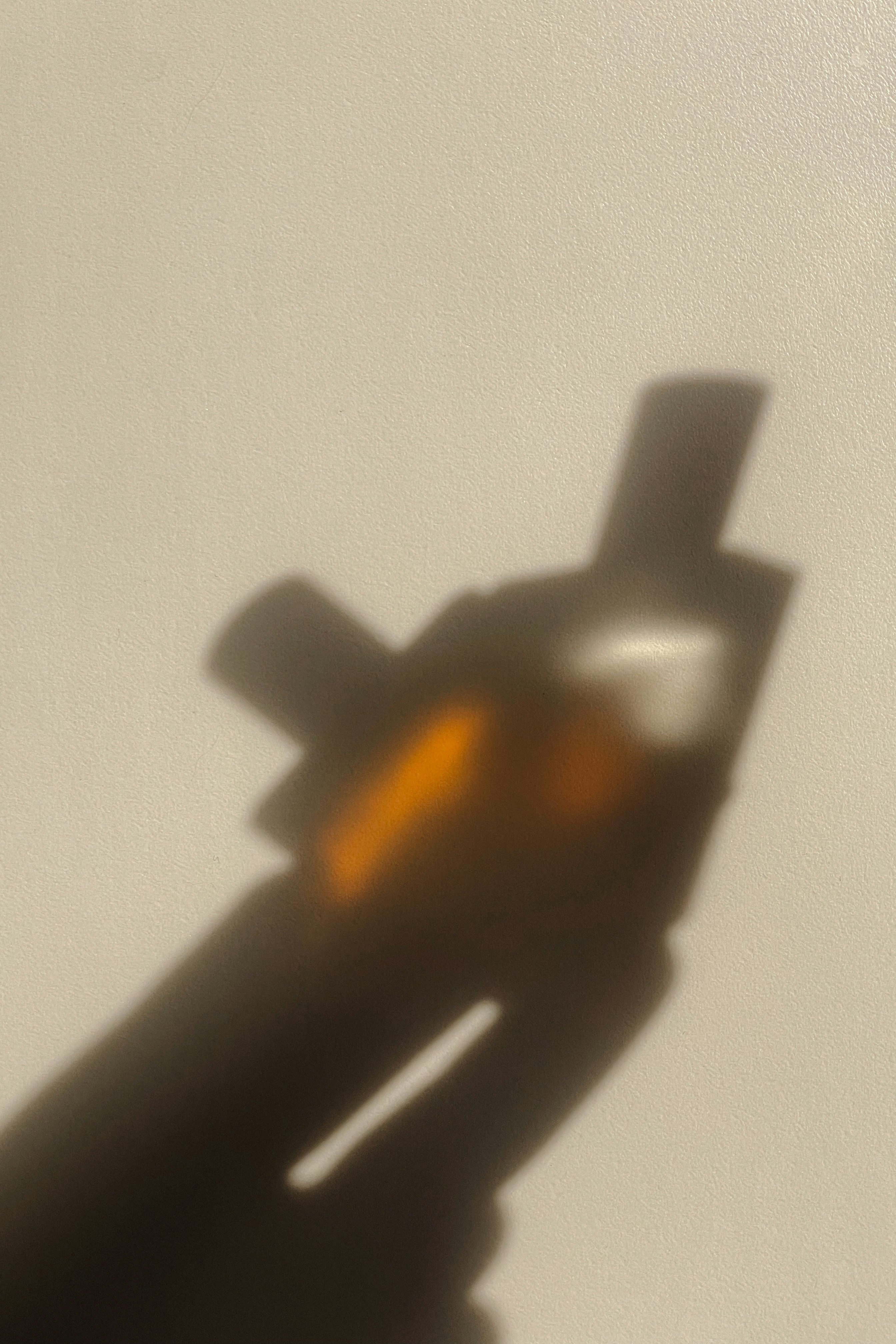 Schattenspiegelung von einer Hand die zwei Parfums hält