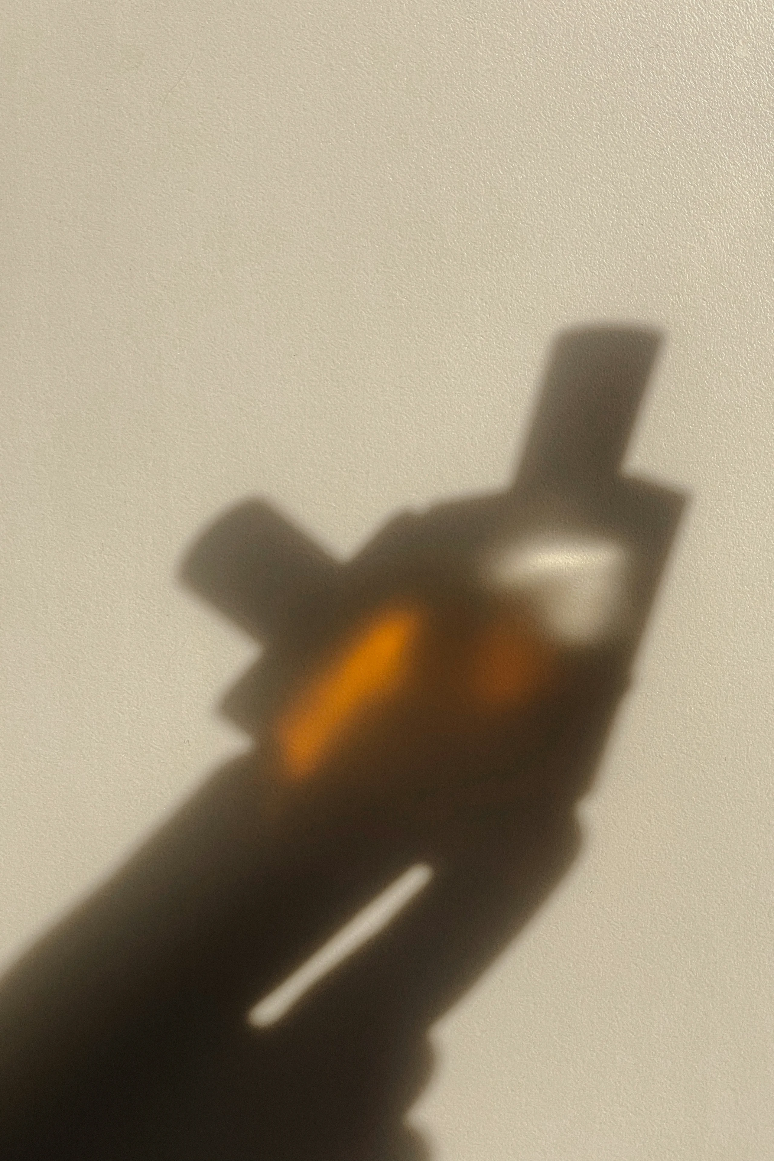 Schattenspiegelung von einer Hand die zwei Parfums hält