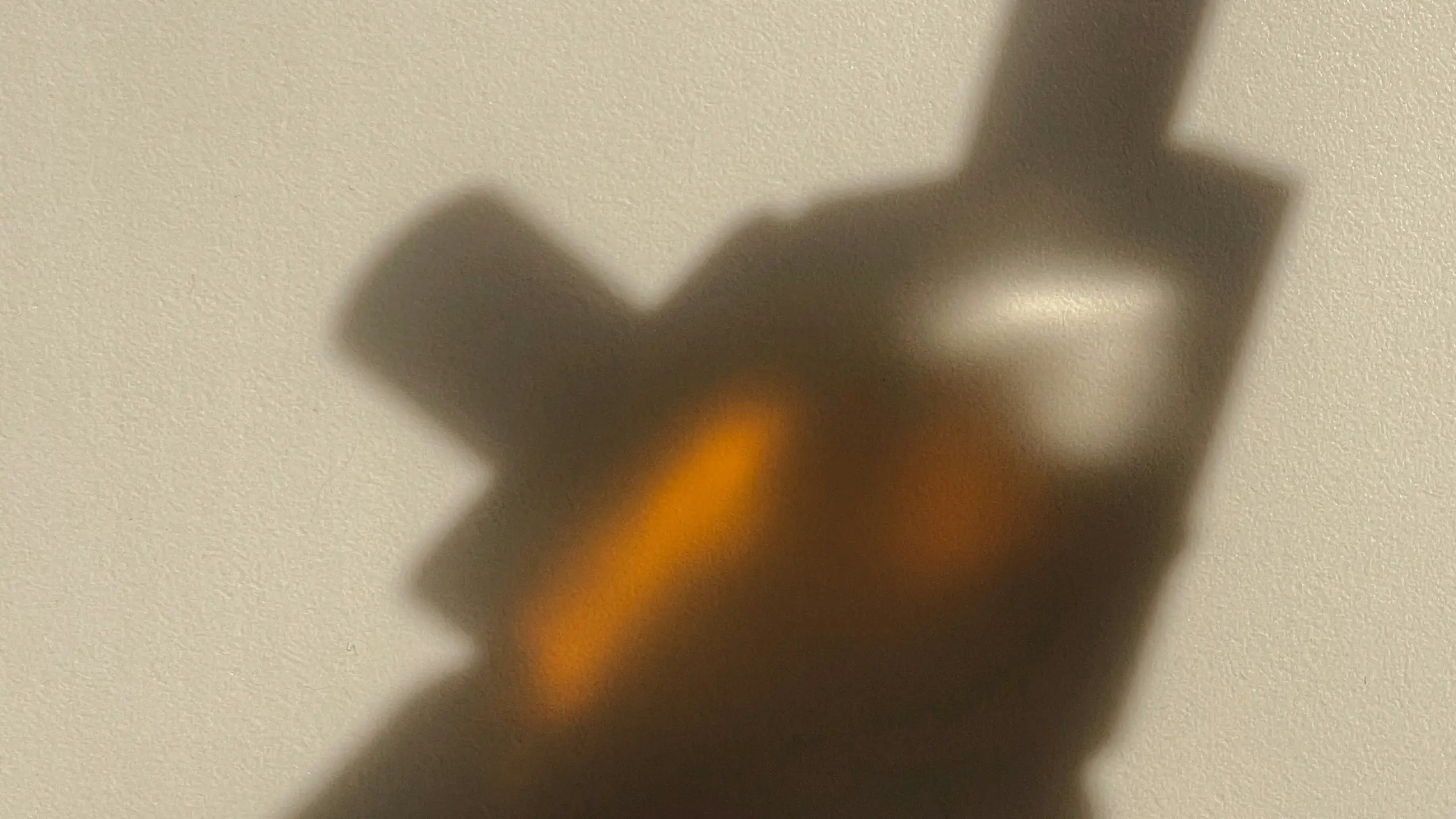 Schattenspiegelung von einer Hand die zwei Parfums hält