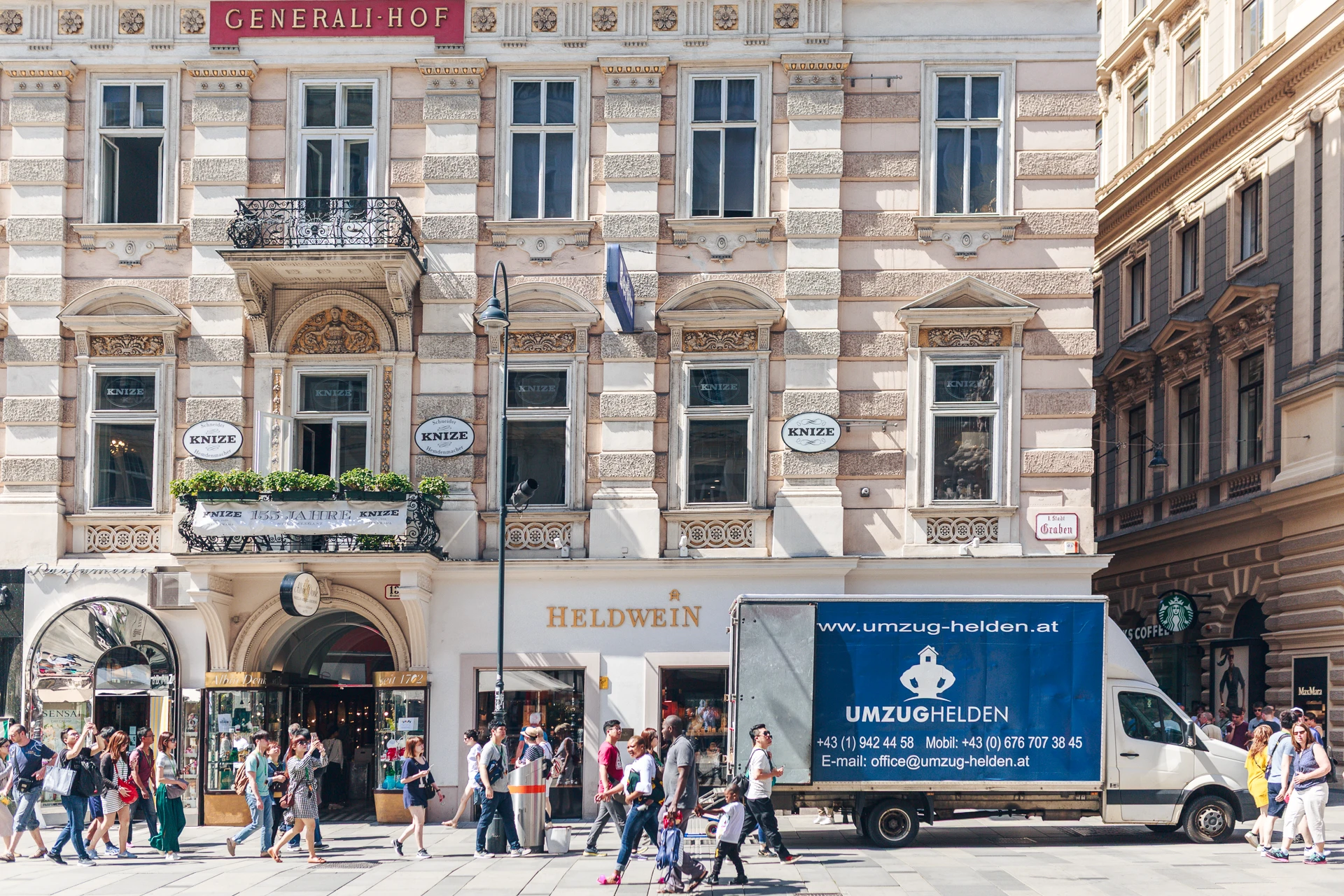 Historische Gebäude und belebte Straßenszene am Graben in Wien mit einem Umzugswagen von Umzug Helden.