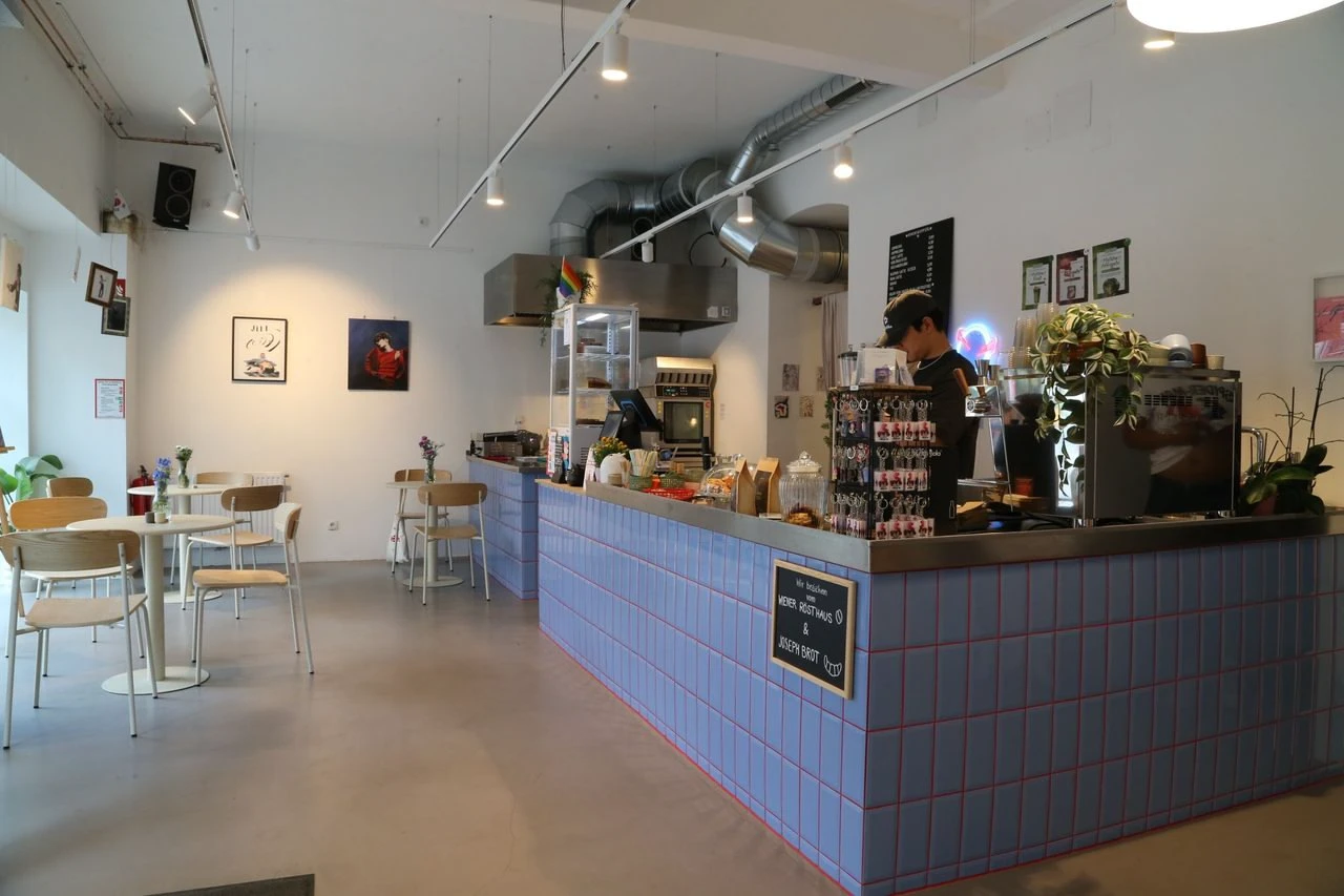 Modernes Café mit blaukacheliger Theke und einem Barista bei der Arbeit.