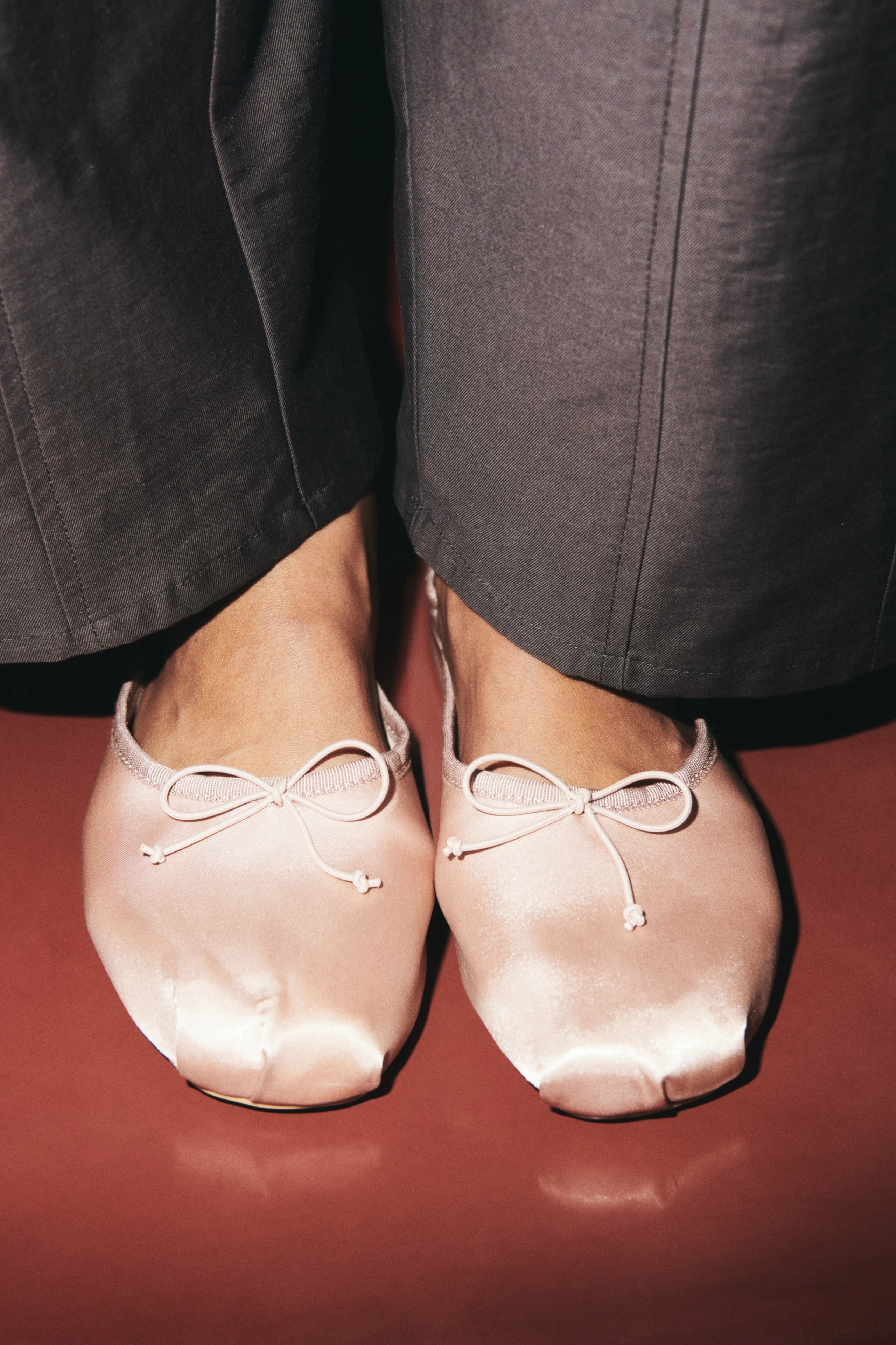 Close-up mit rosa Satin Ballerina mit Schleifen und grauer Anzughose